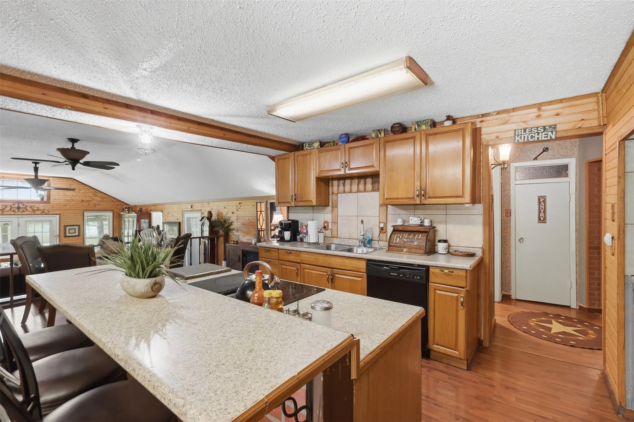 Functional kitchen workspace featuring expansive counter space, double sink, upper cabinets, and direct access to adjacent rooms.