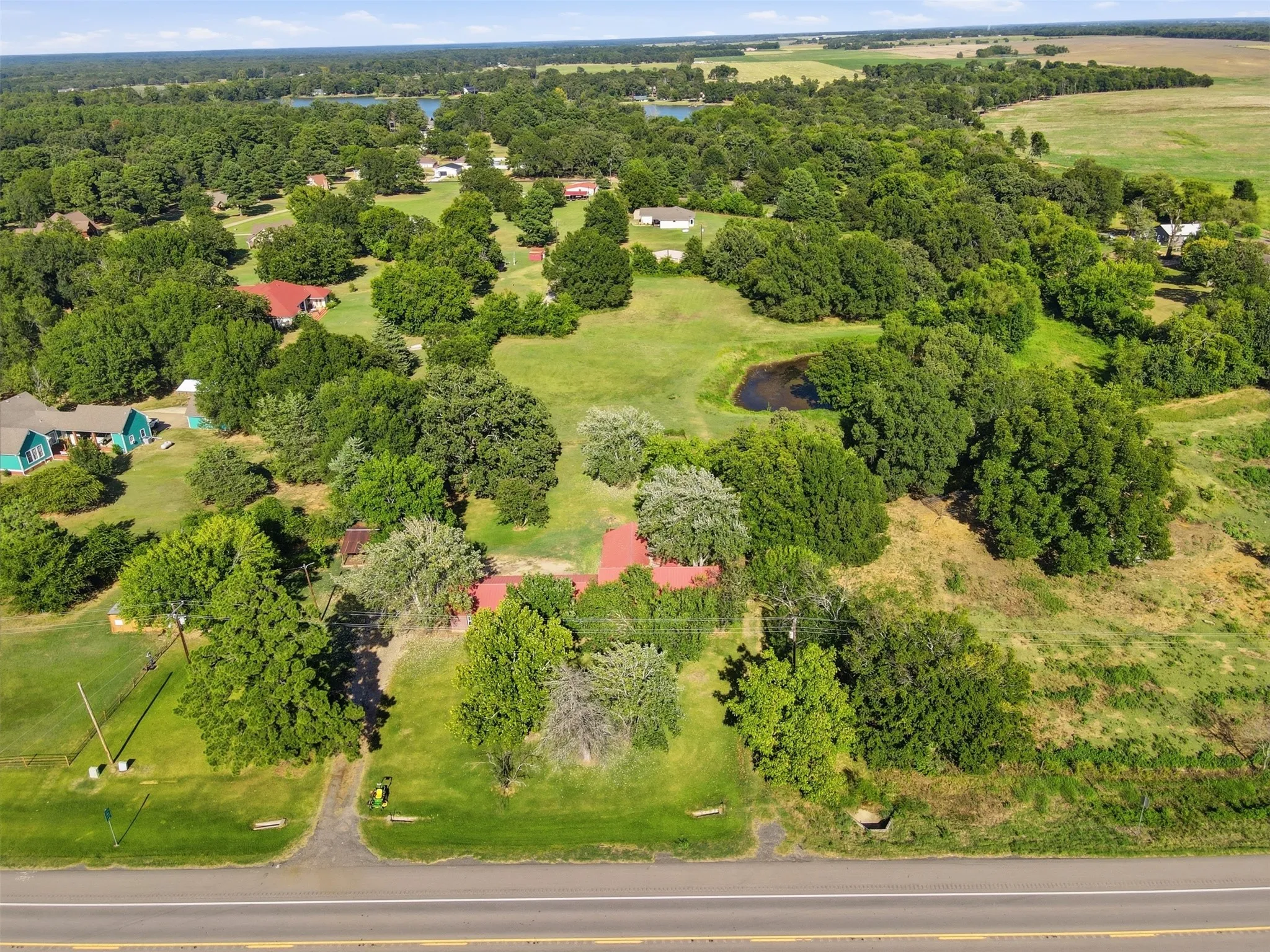 High-altitude aerial view capturing the home set amidst rolling country terrain and dense tree cover.