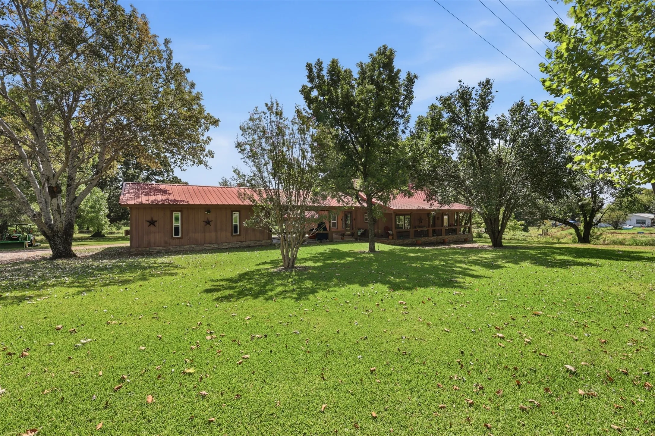 Wide view of the expansive lawn area surrounding the home, shaded by mature trees.
