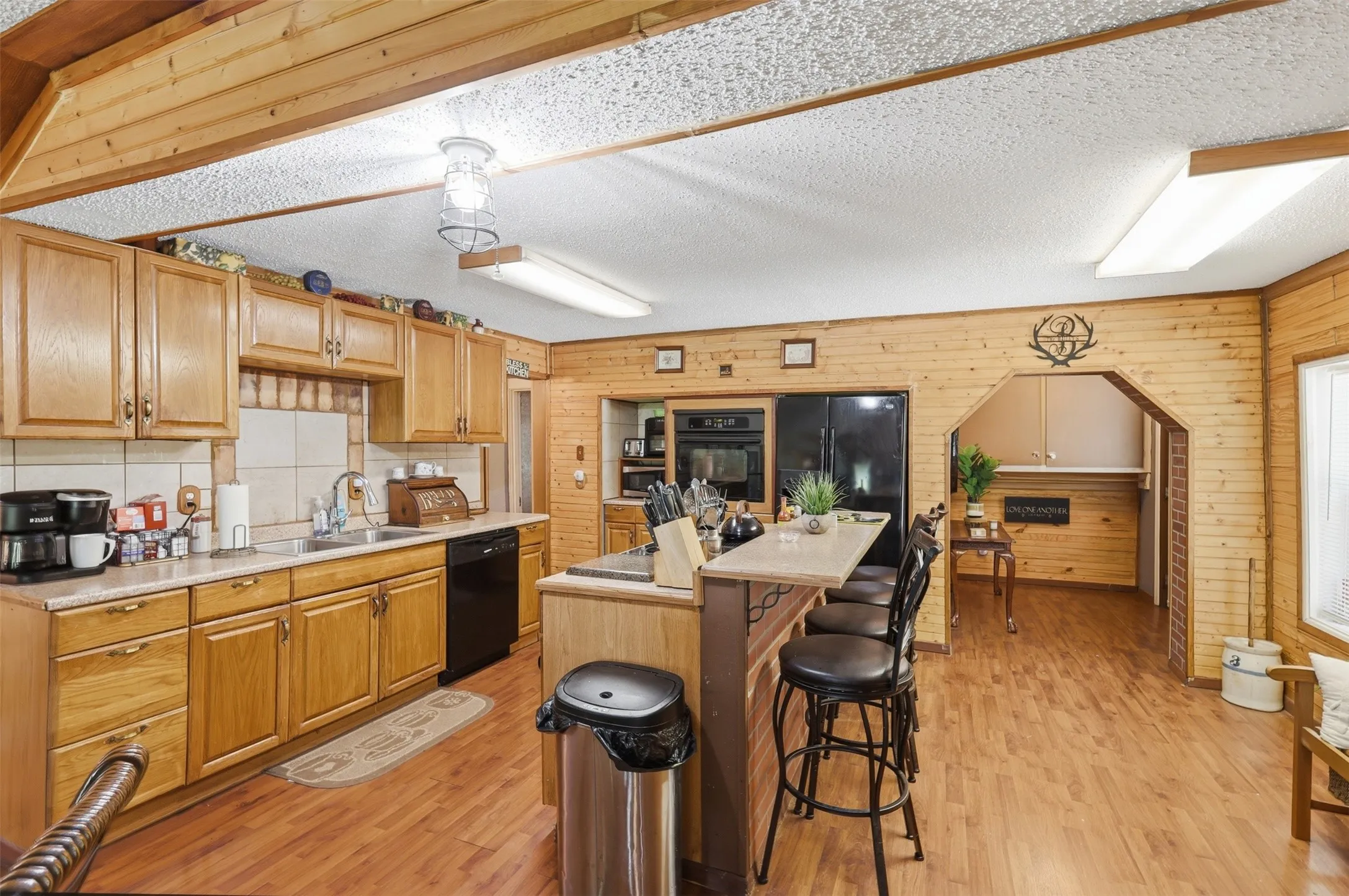 Spacious country kitchen with abundant wood cabinetry, breakfast bar island, and rich wood-tone flooring.