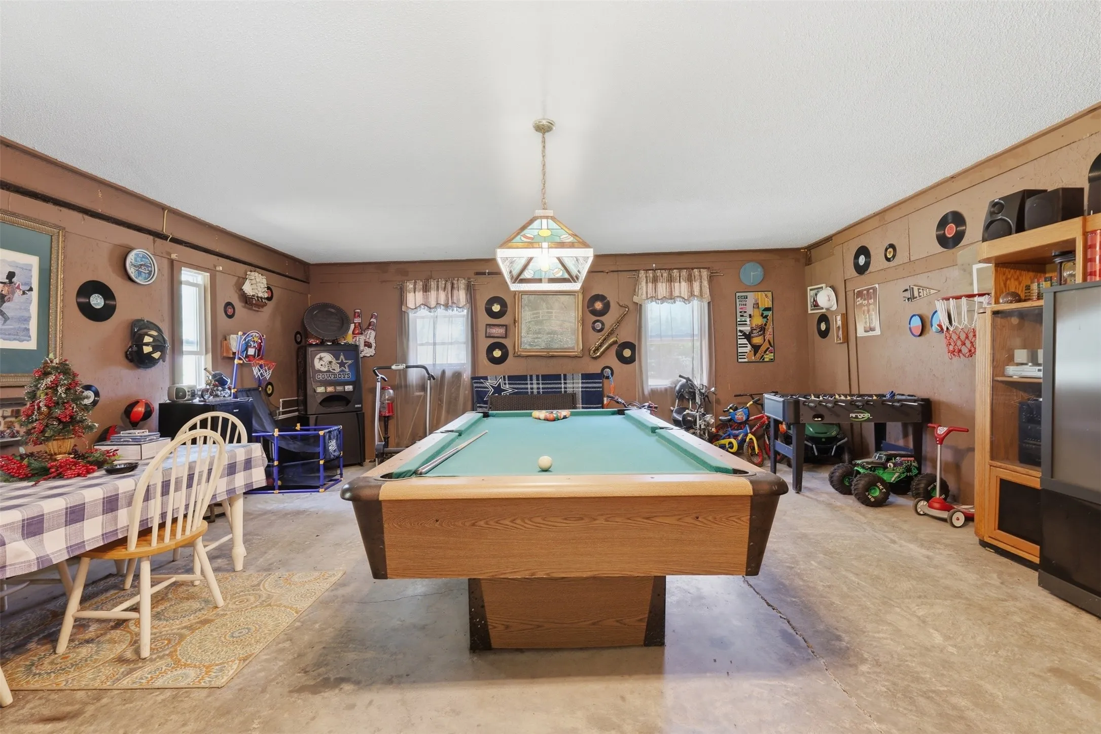 Spacious game room setup featuring a full-size pool table, decorative lighting, and paneled walls.
