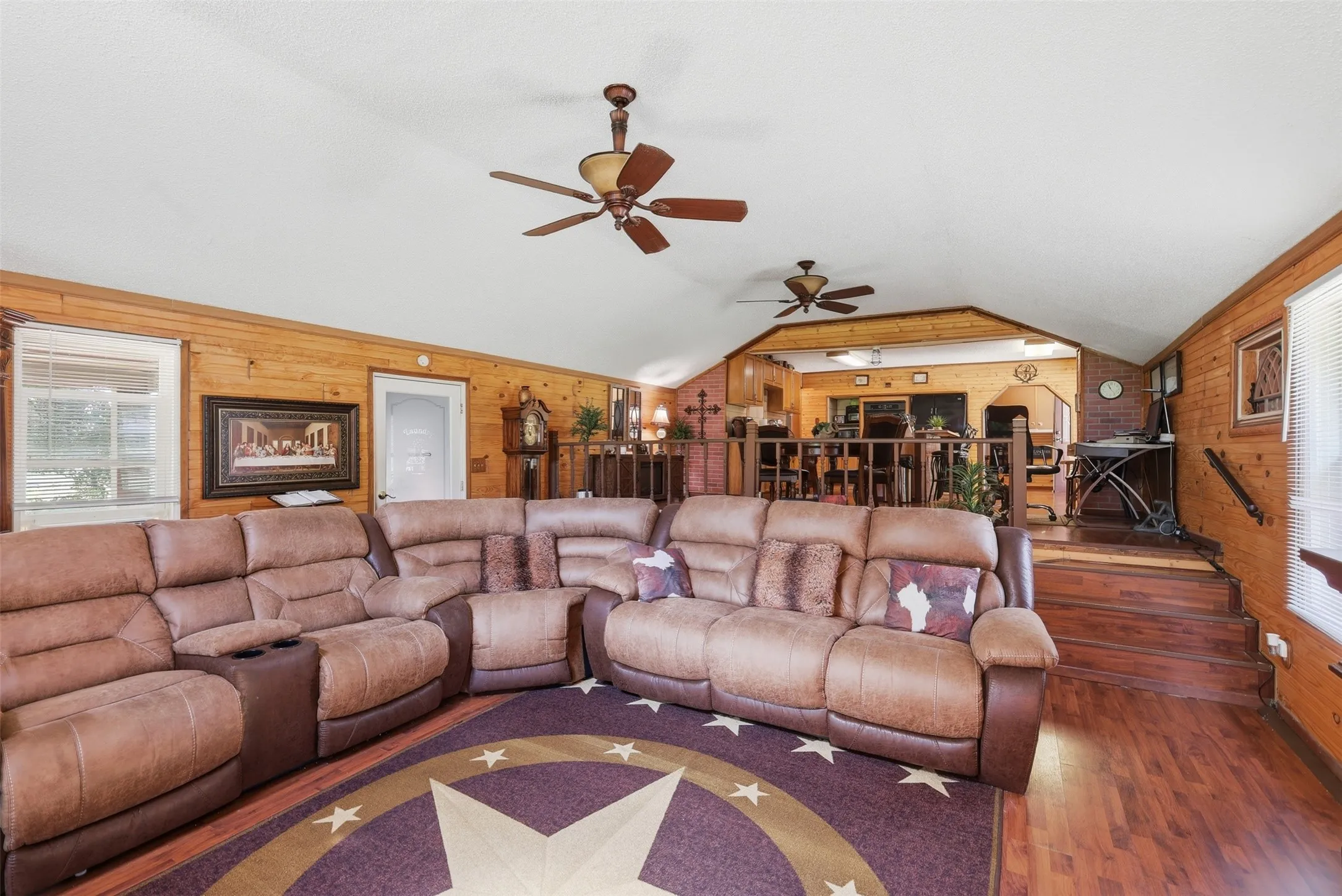Alternate angle of the spacious living room highlighting rich wood flooring, star floor inlay, and open layout.