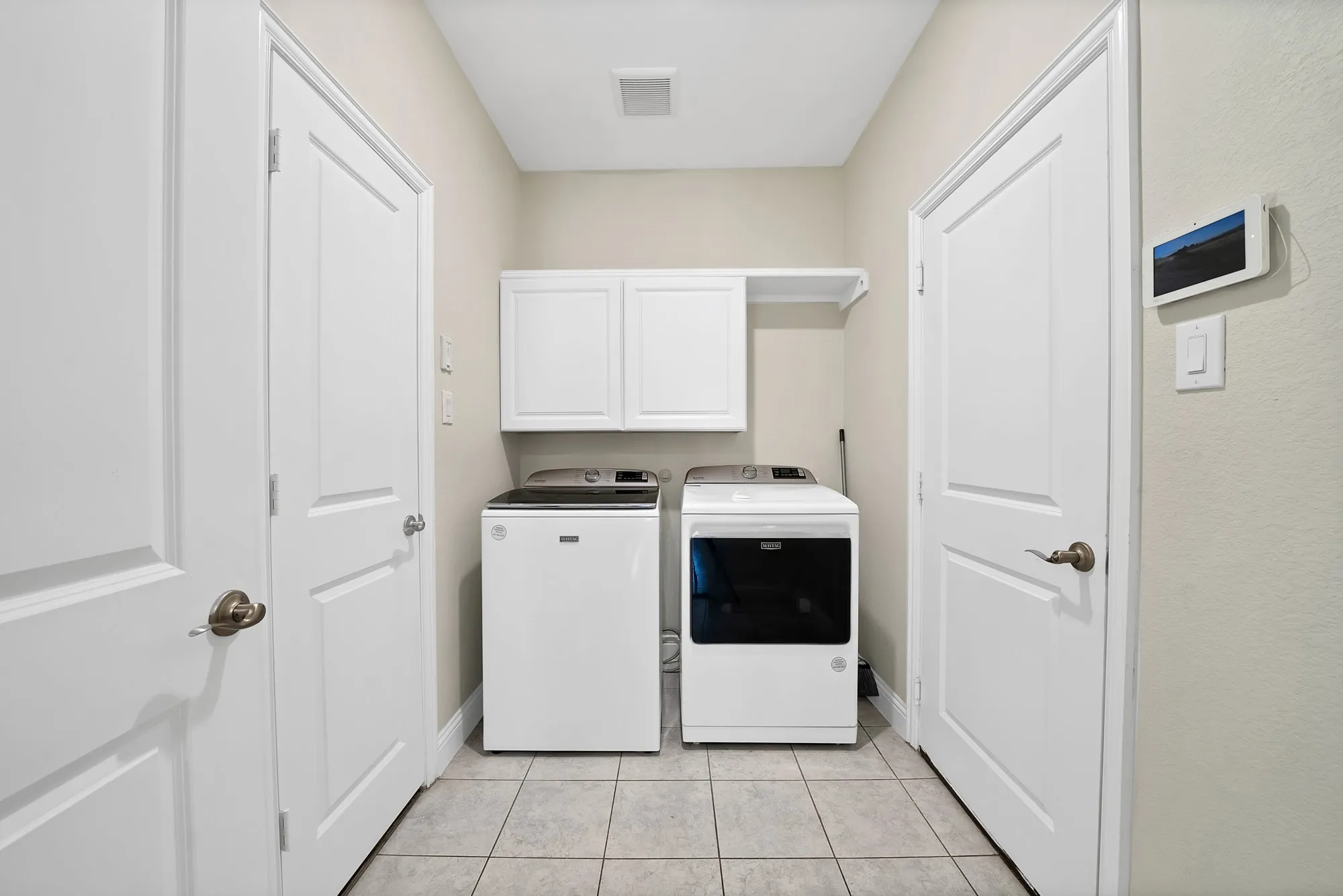 Utility room featuring white cabinetry, a built-in shelf, and tile flooring