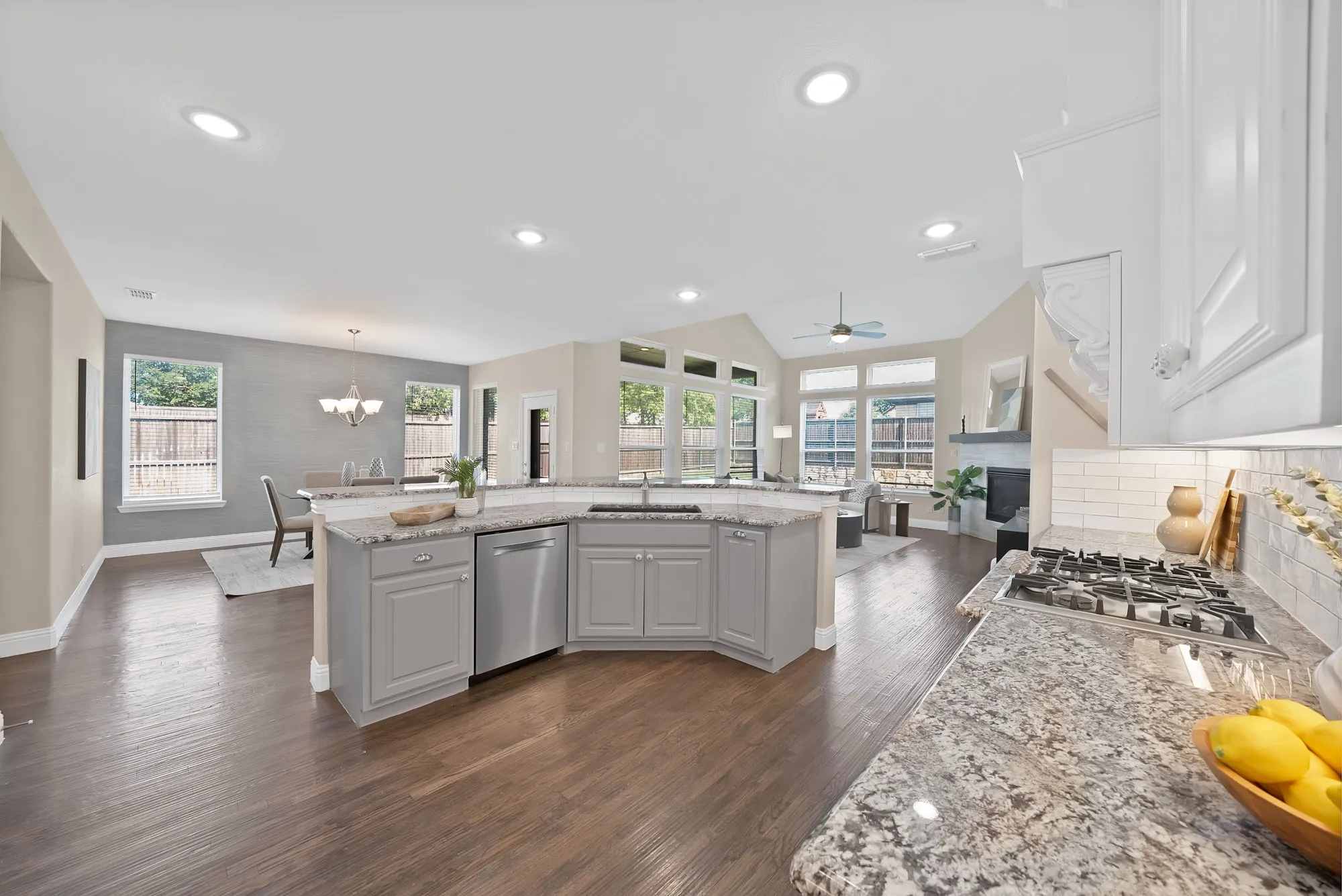 Wood-finish flooring throughout, kitchen with stone countertops, gray cabinetry, and stainless steel dishwasher