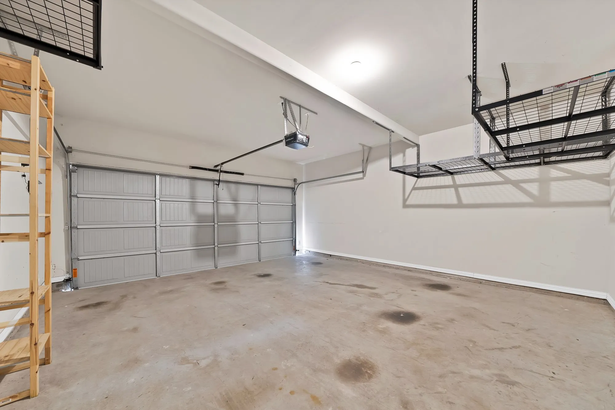 Concrete flooring with overhead storage racks, an automatic garage door opener, and a panel garage door
