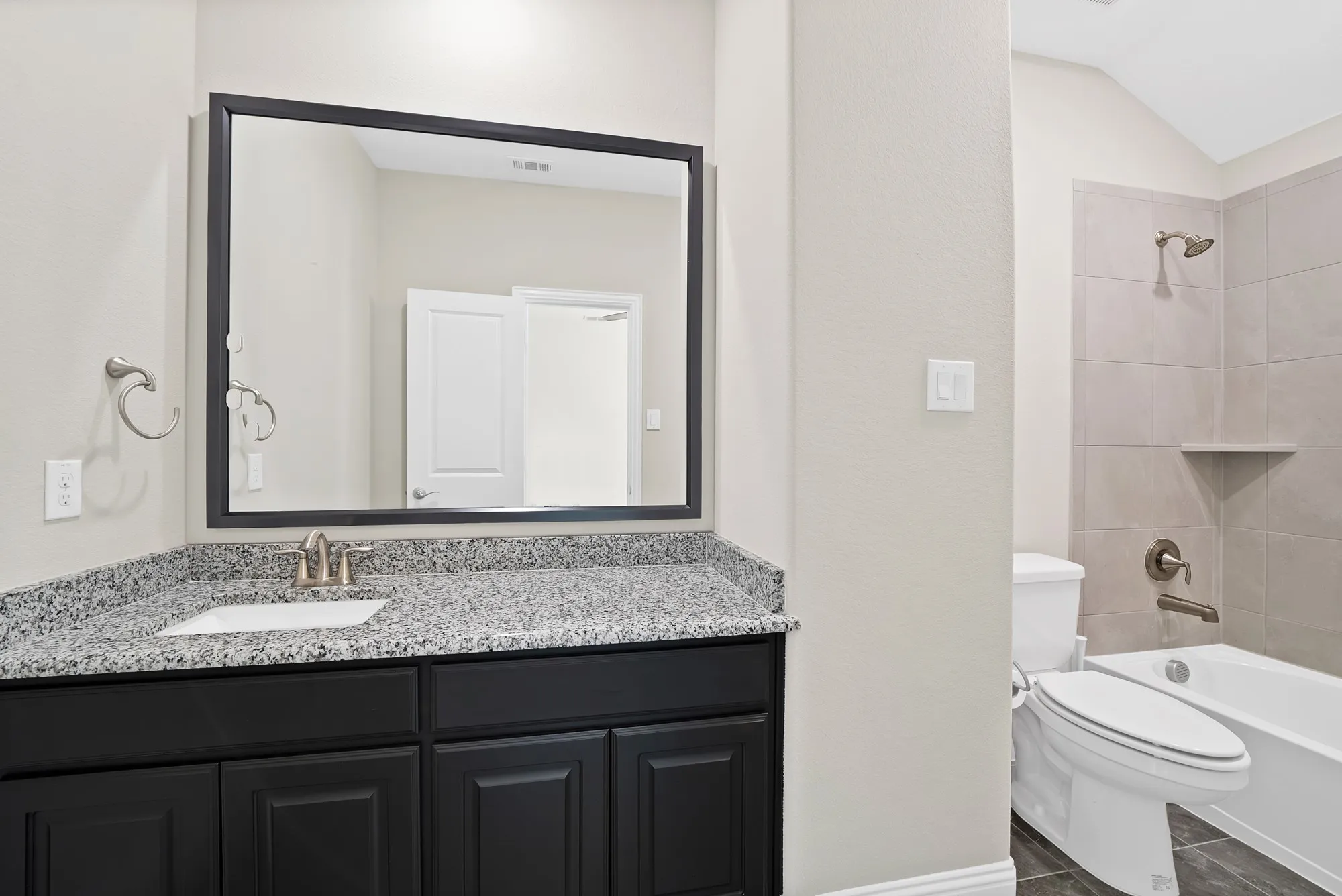 Black cabinetry with a granite-style countertop and an undermount sink