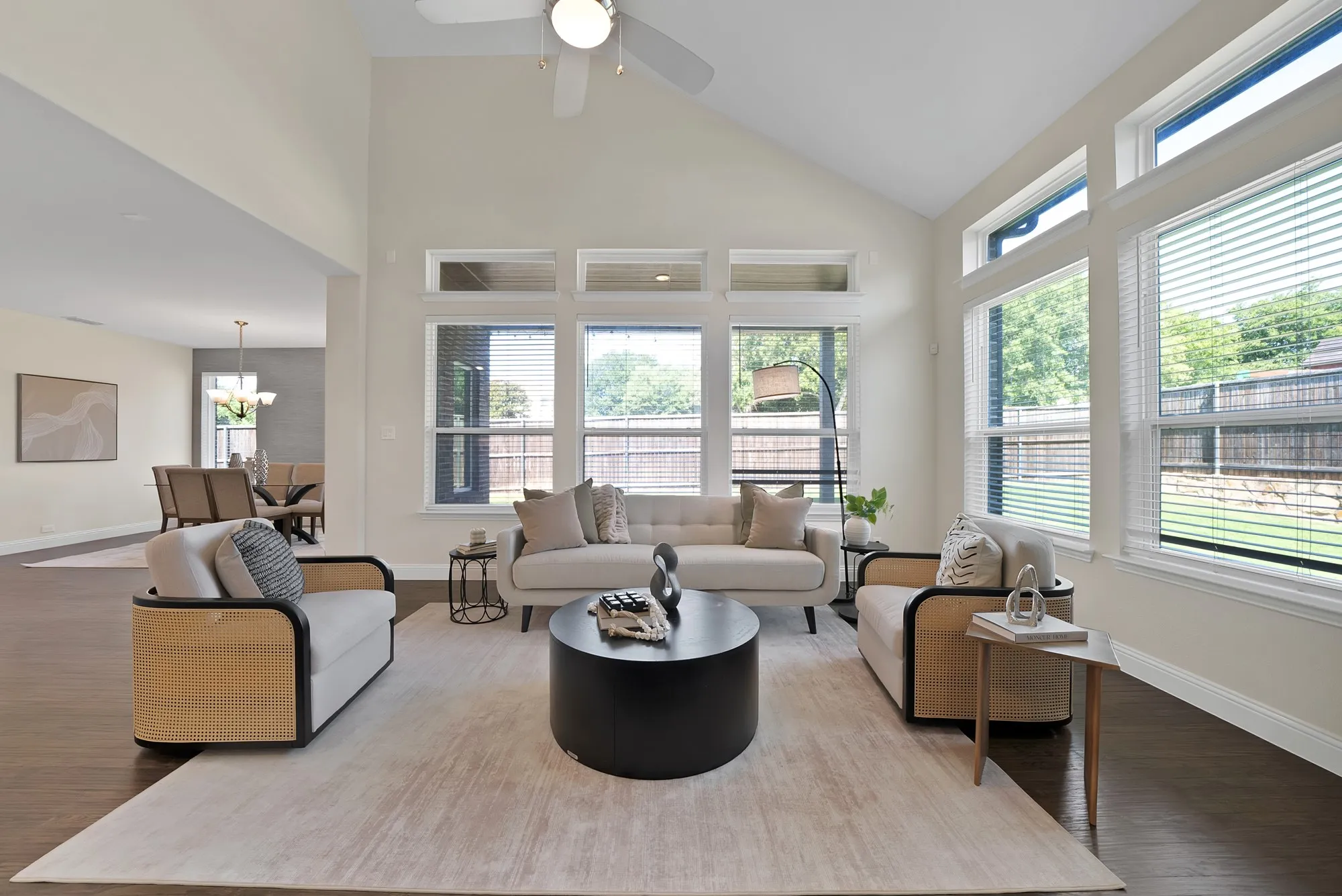 Vaulted ceiling with a ceiling fan, wood-finish flooring, and a wall of windows featuring transom accents