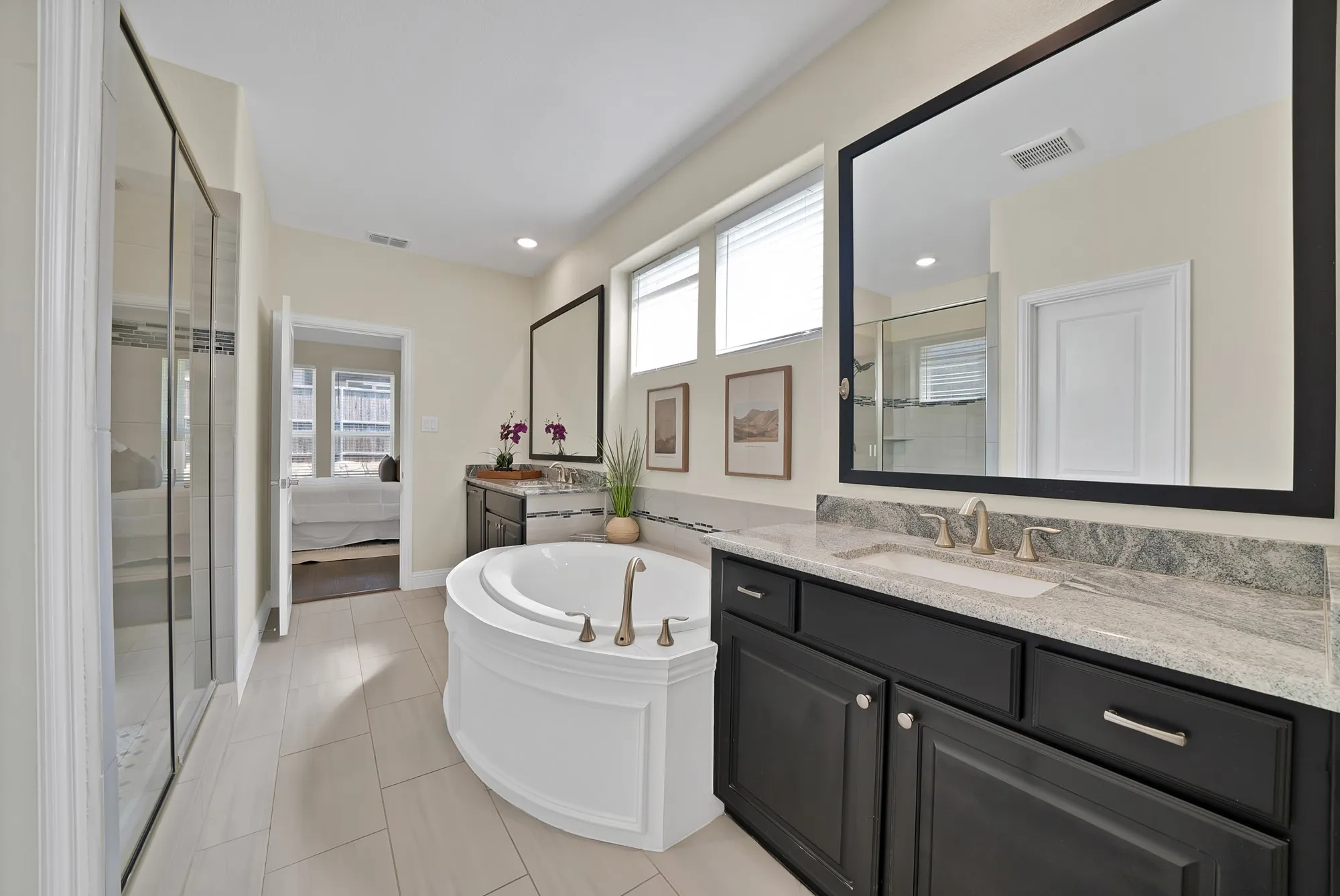 Dual vanity with stone countertop, large soaking tub, glass-enclosed shower, and tile flooring