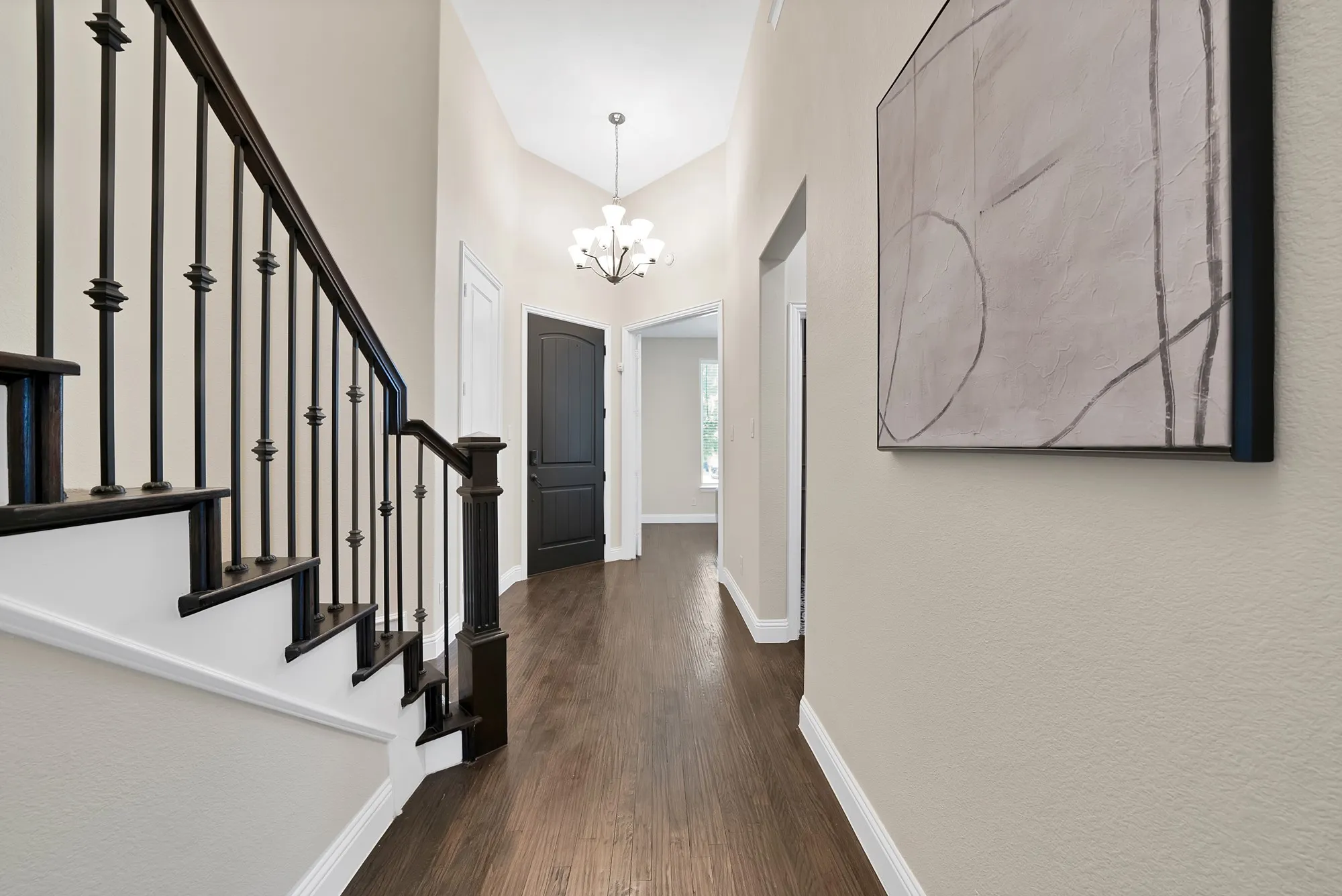 Dark wood-finish flooring with a complementary staircase featuring dark balusters