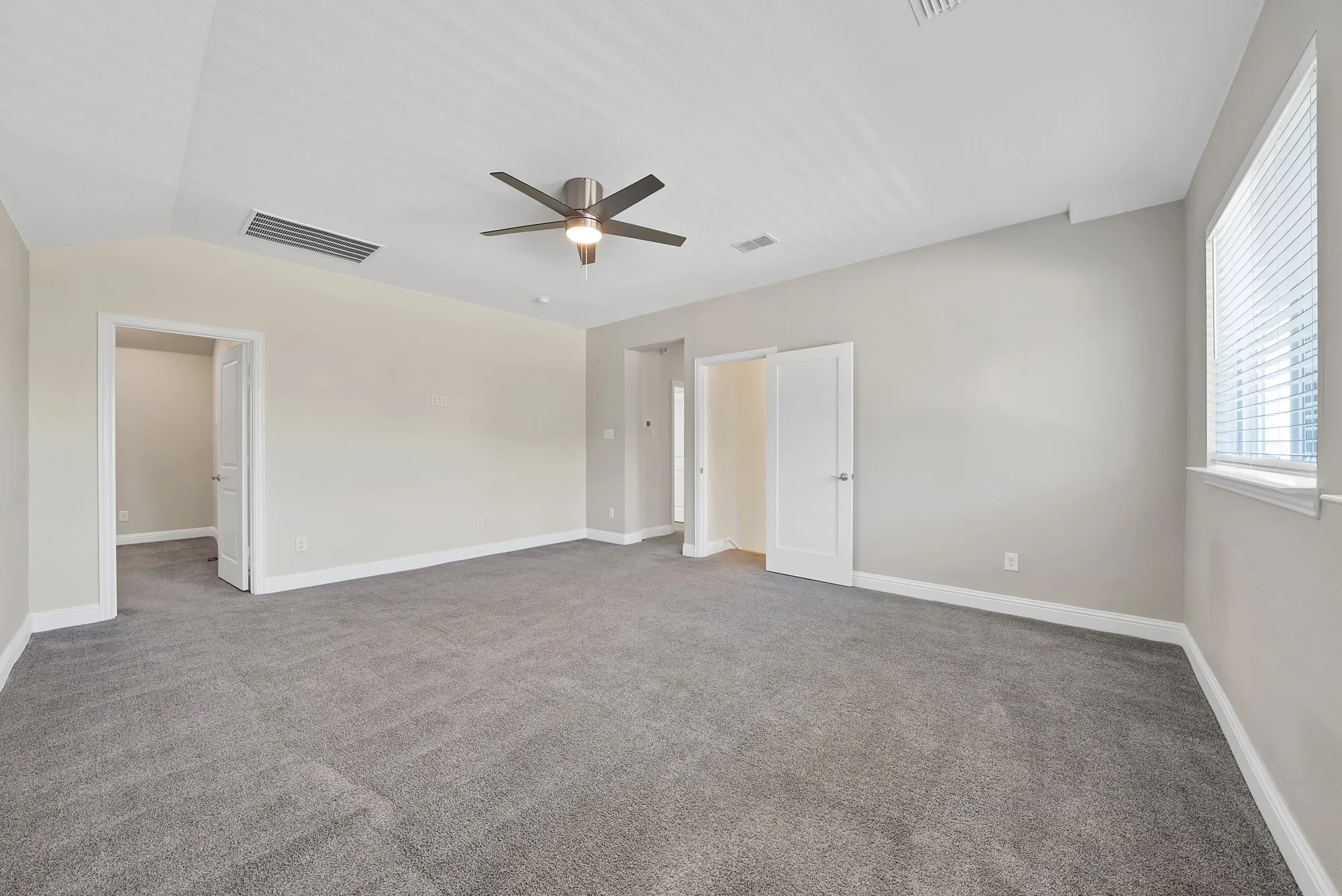 Spacious room featuring neutral wall tones, gray carpeting, a ceiling fan, and a window with horizontal blinds