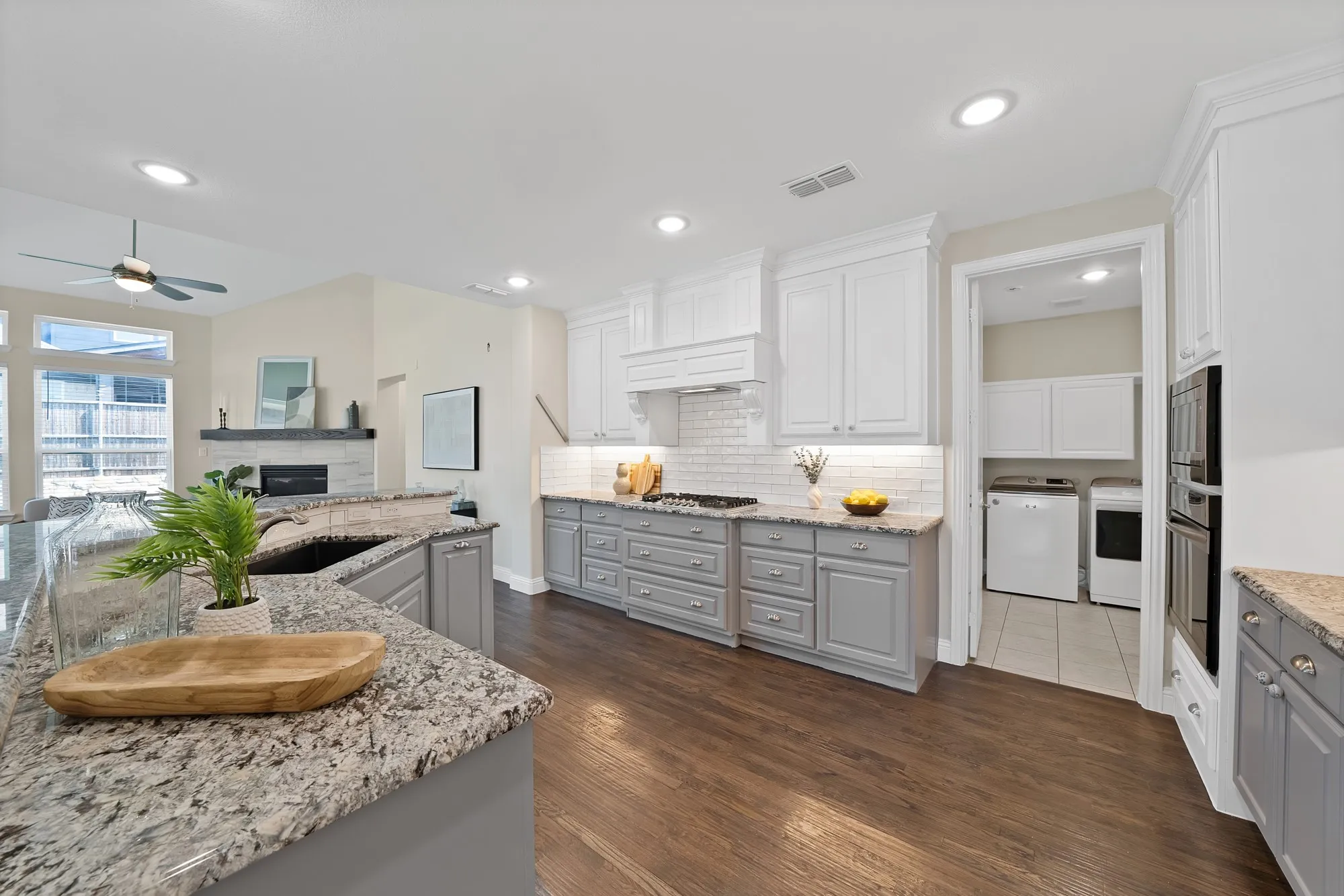 Kitchen featuring granite countertops, wood-finish flooring, white upper cabinetry, gray lower cabinetry, and a subway tile backsplash