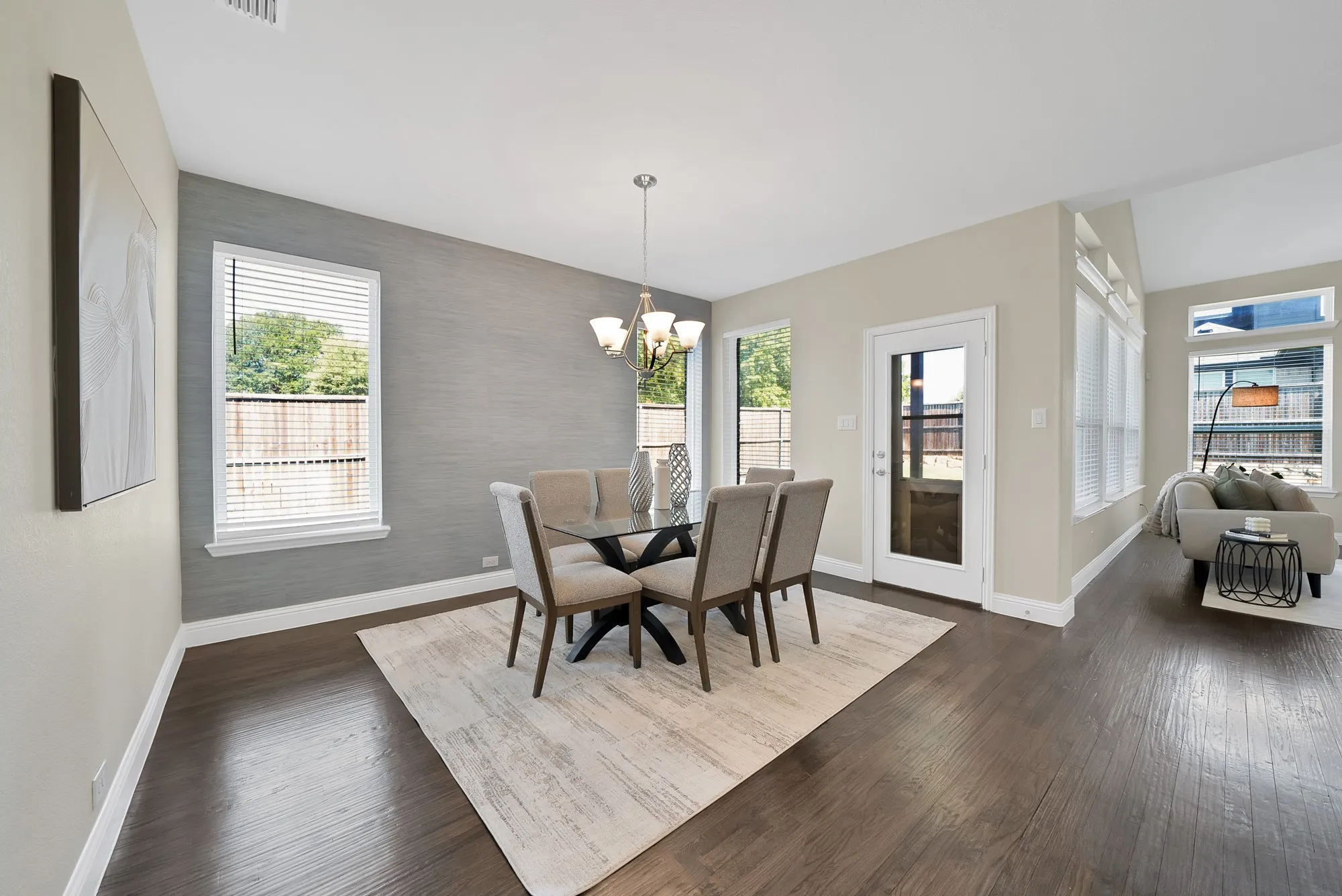 Rich wood-finish flooring throughout, complemented by a contemporary chandelier and recessed lighting