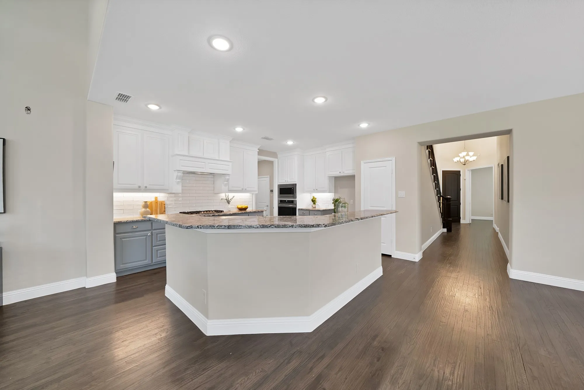 Open-concept kitchen featuring an eat-at island, recessed lighting, white upper cabinetry, and contrasting lower cabinetry