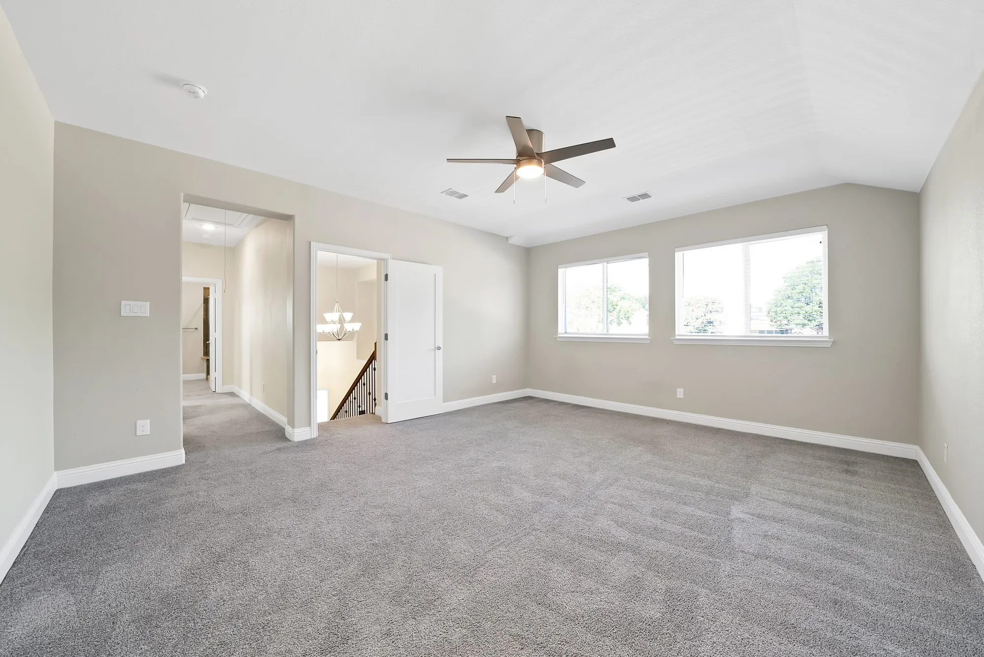 Spacious room featuring vaulted ceilings, light gray wall tones, and gray carpeting