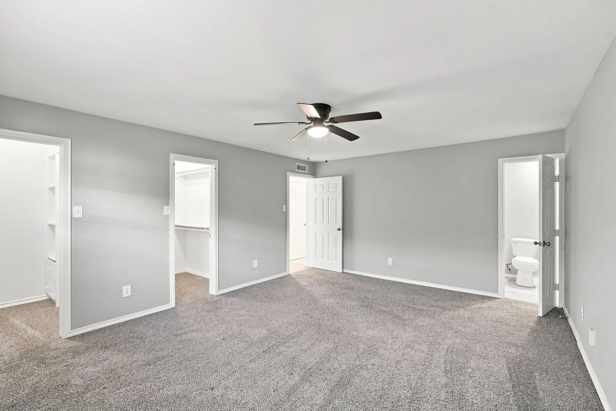 Spacious room featuring gray walls, gray carpet, a ceiling fan with integrated lighting, and white trim