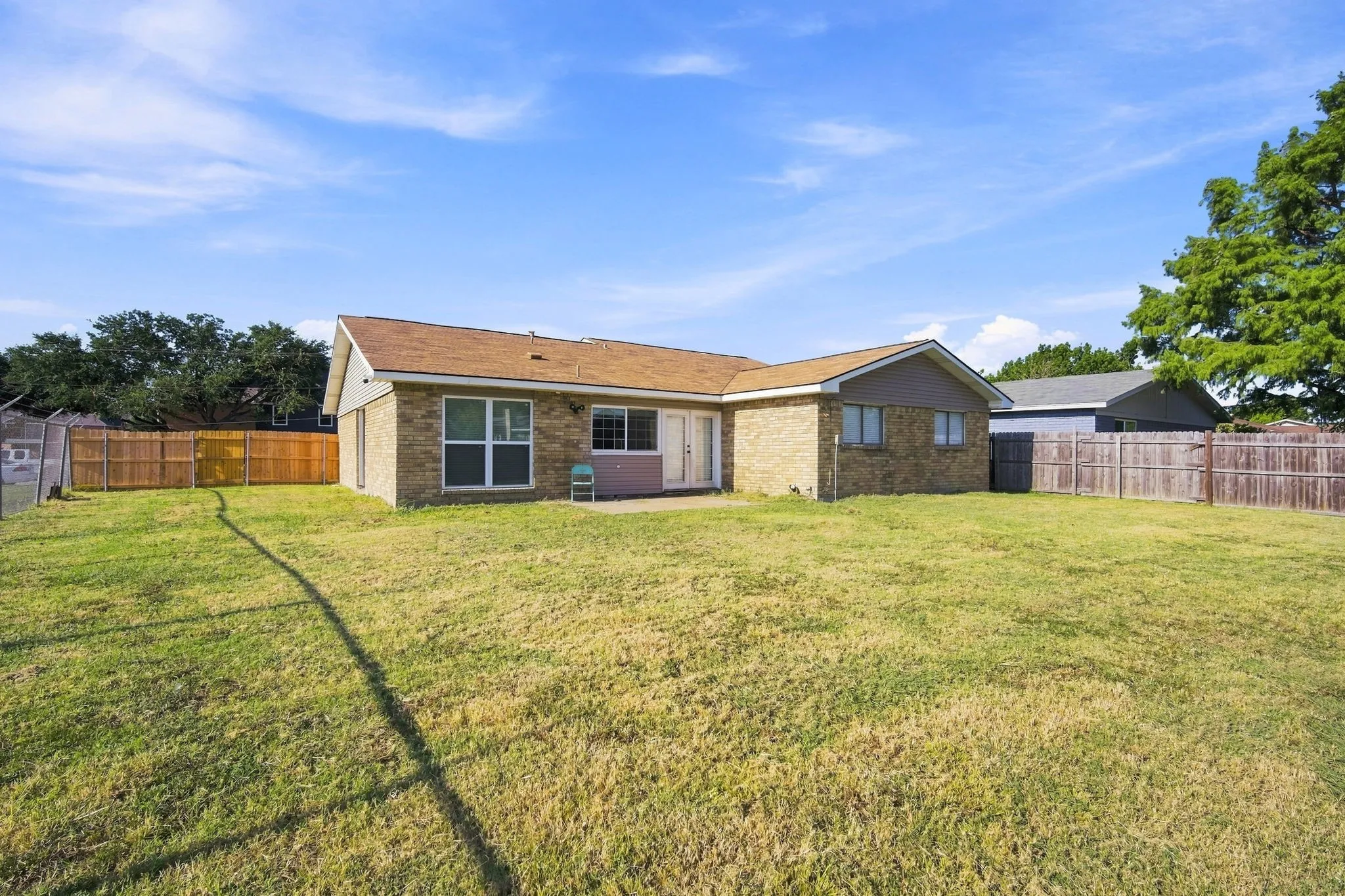 Expansive grass yard with wood fencing and a concrete patio