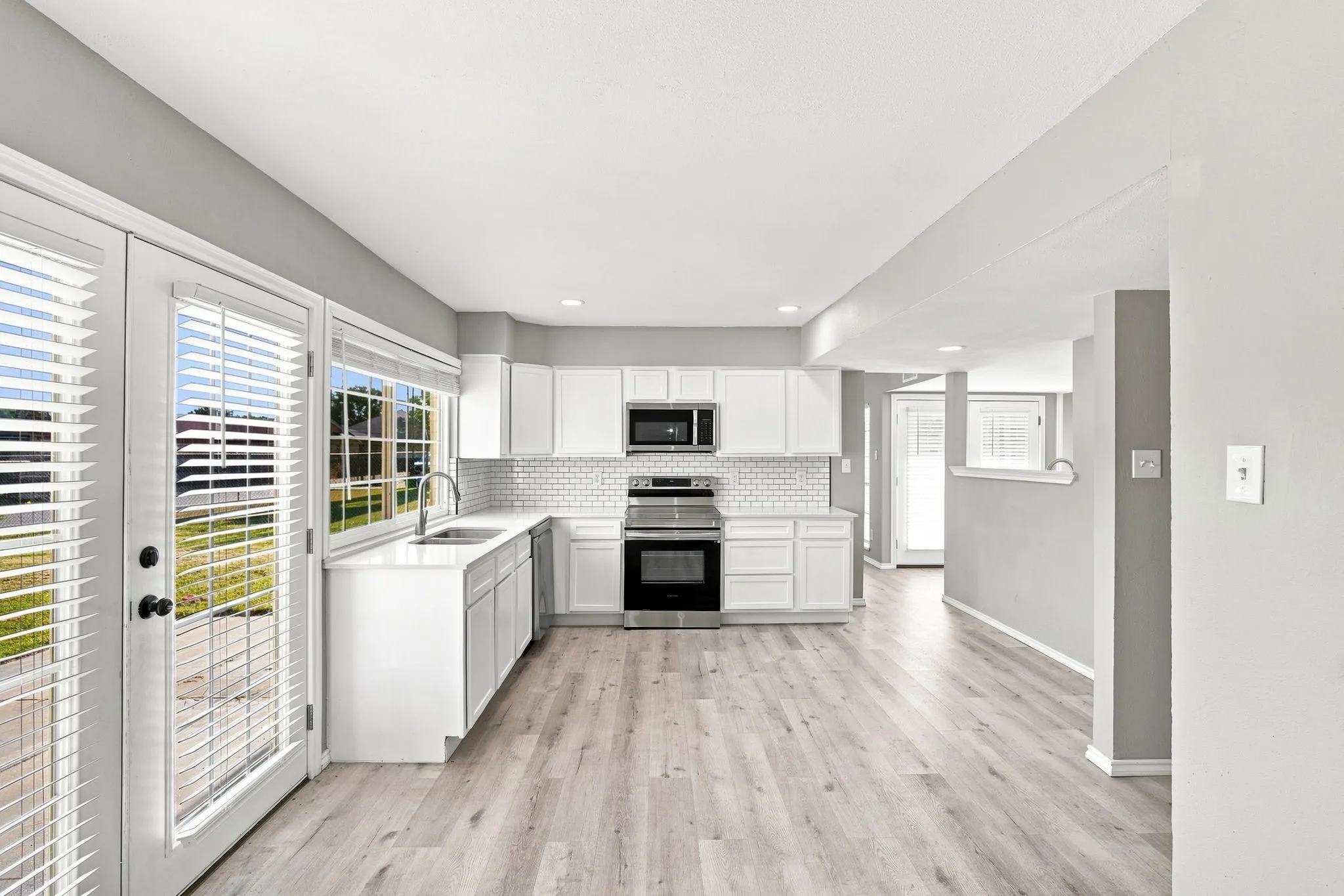 Kitchen featuring light wood-finish flooring, white cabinetry, stainless steel appliances, and a tile backsplash