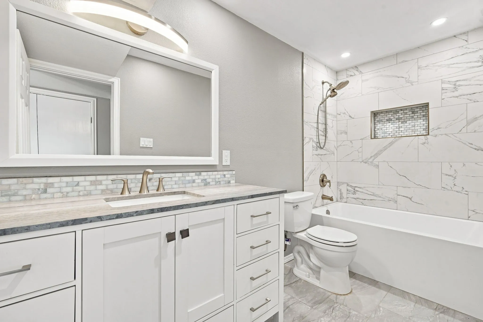 White shaker-style vanity with a light-toned countertop, a rectangular undermount sink, and a framed mirror