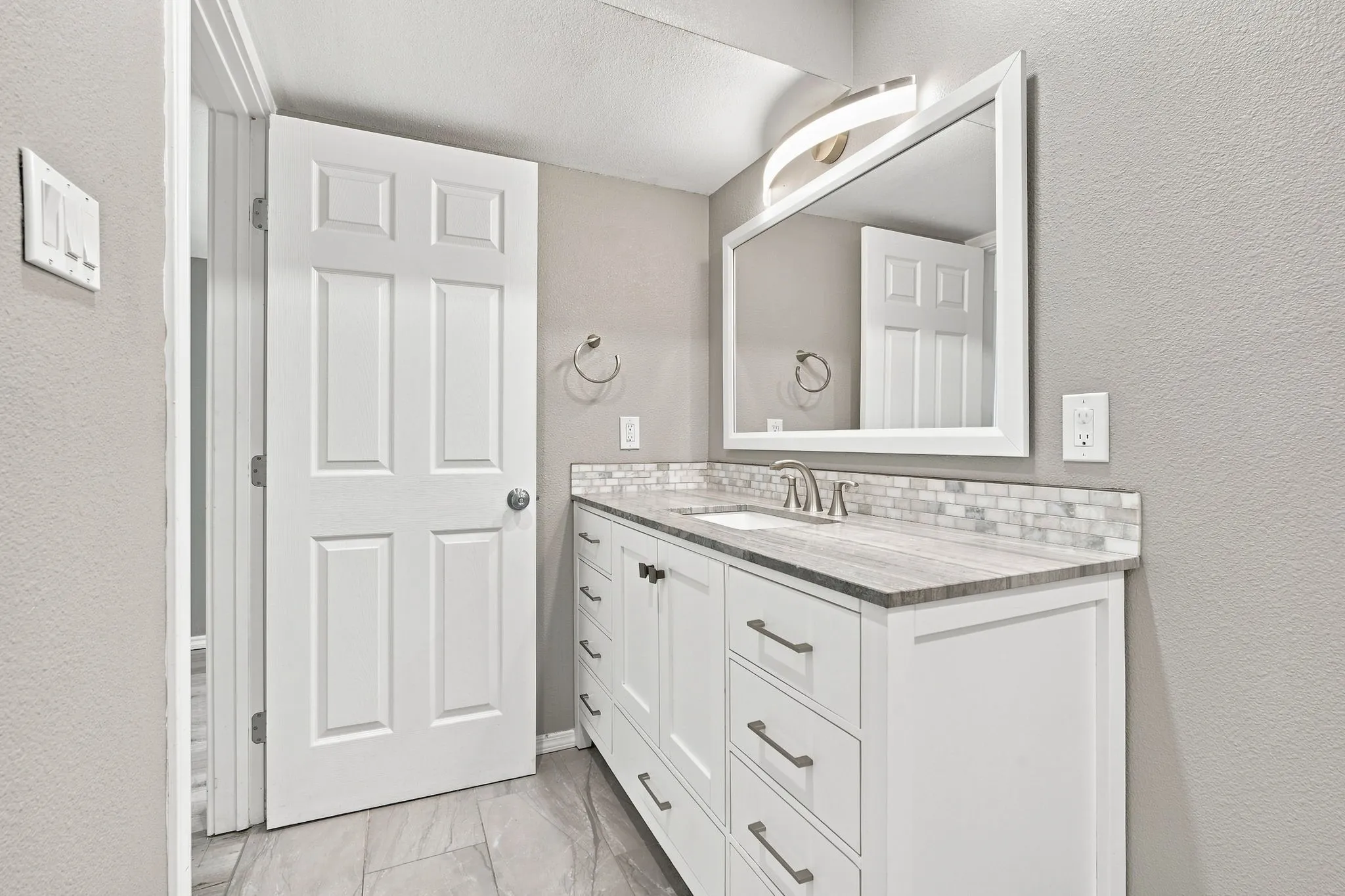 White vanity with matte black hardware, integrated sink, and stone-look countertop