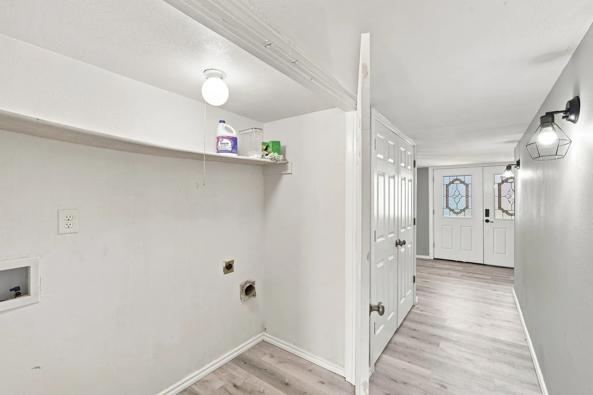 Utility area with wall shelving, washer/dryer hookups, and wood-finish flooring