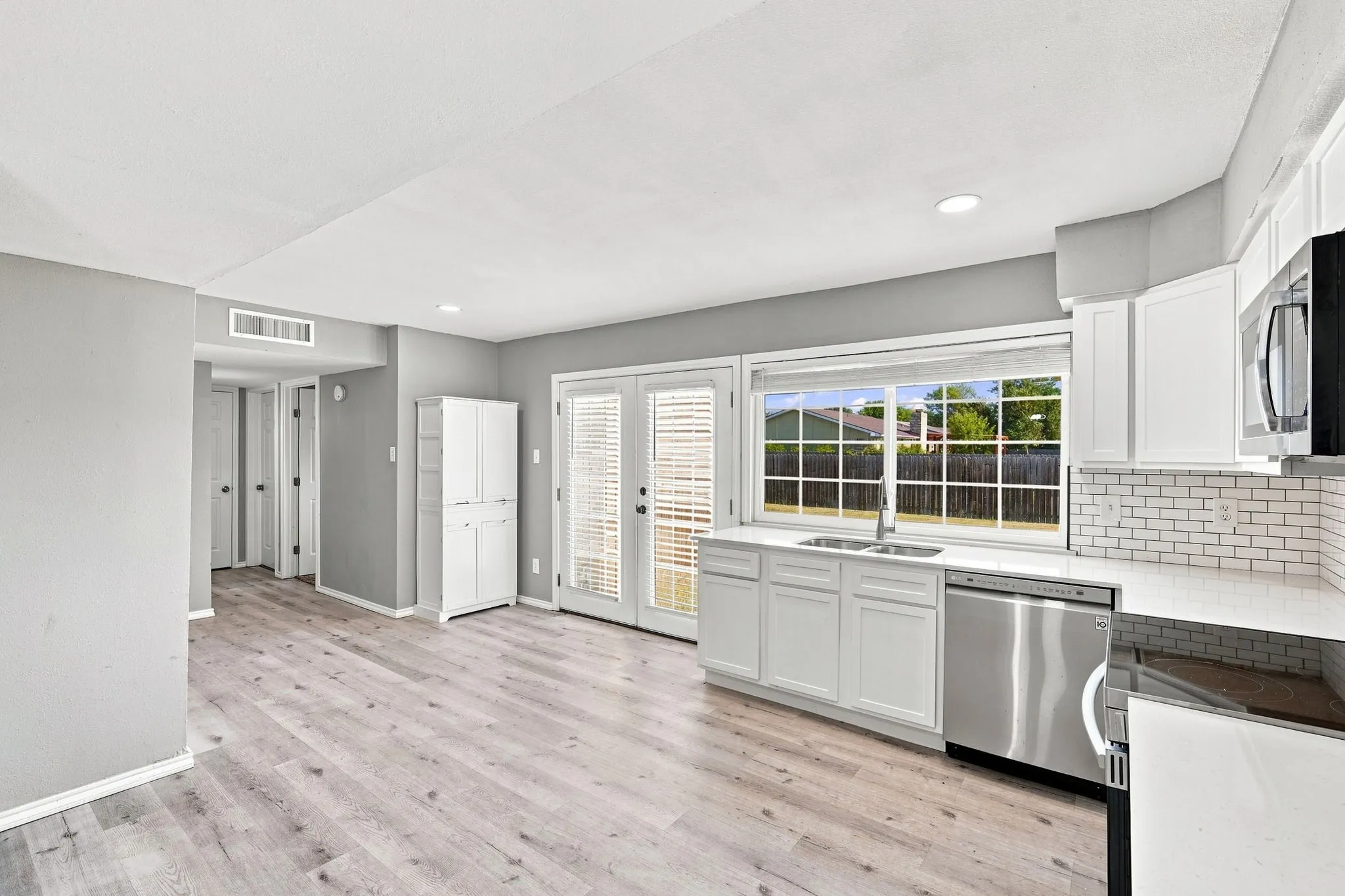 Kitchen with white cabinetry, stainless steel appliances, white subway tile backsplash, and light wood-finish flooring