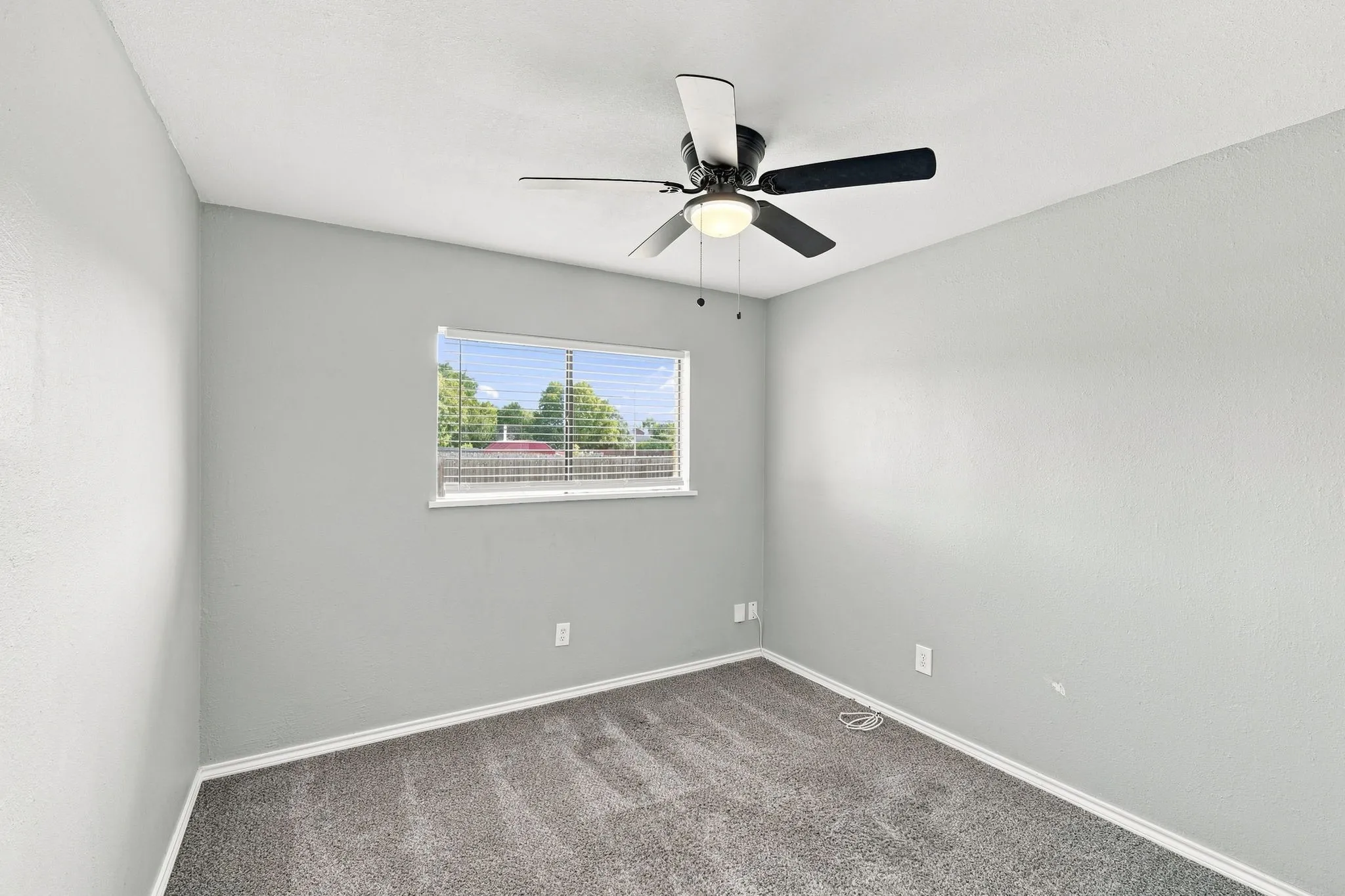 Bright and spacious bedroom featuring neutral gray walls, soft recessed lighting, and a modern ceiling fan with integrated light fixture