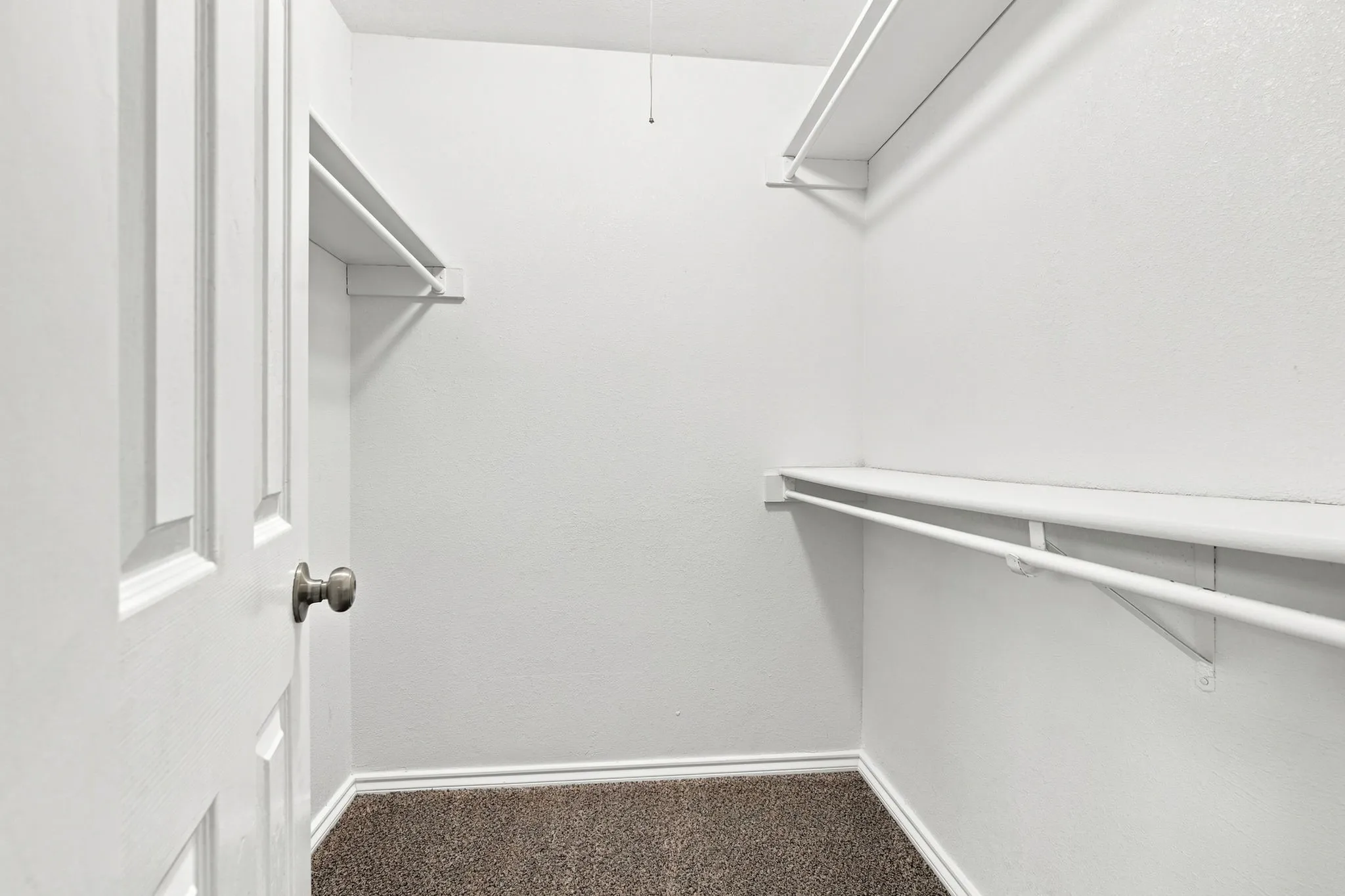 Walk-in closet with wall-mounted shelving and hanging rods