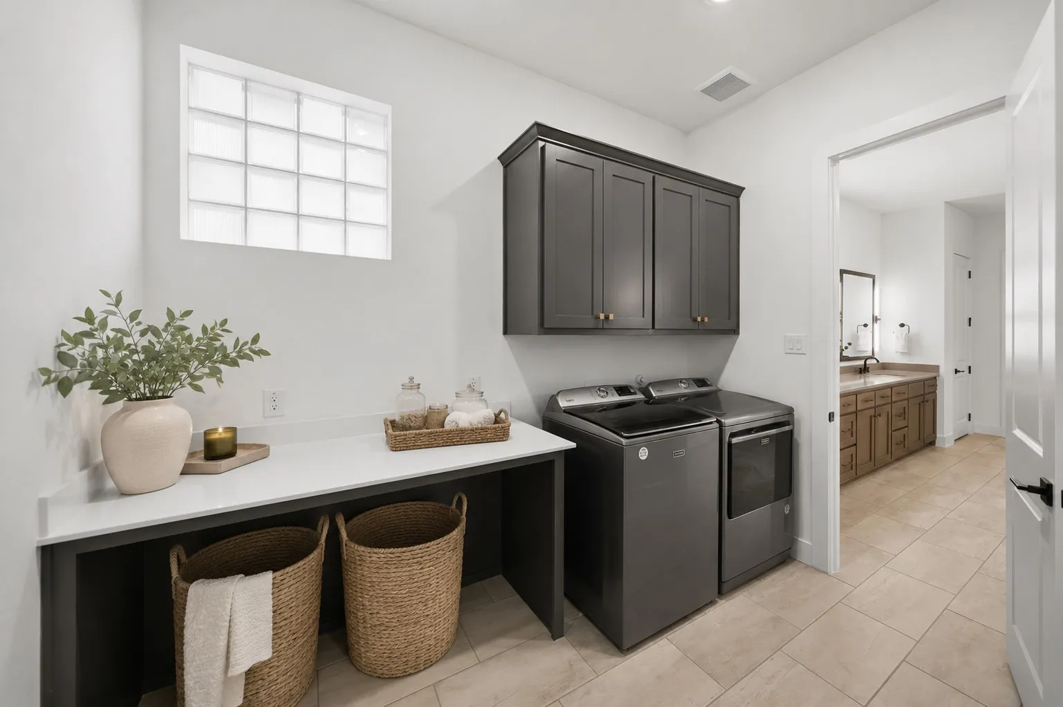 Laundry area with dark cabinetry, white countertops, and a built-in work surface and direct access from primary bathroom.