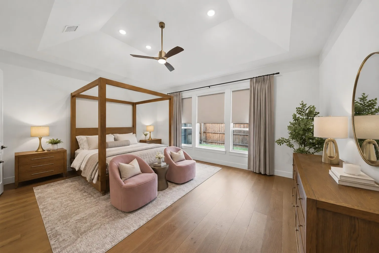 Tray ceiling with recessed lighting, wood-finish flooring, and multiple windows with roller shades