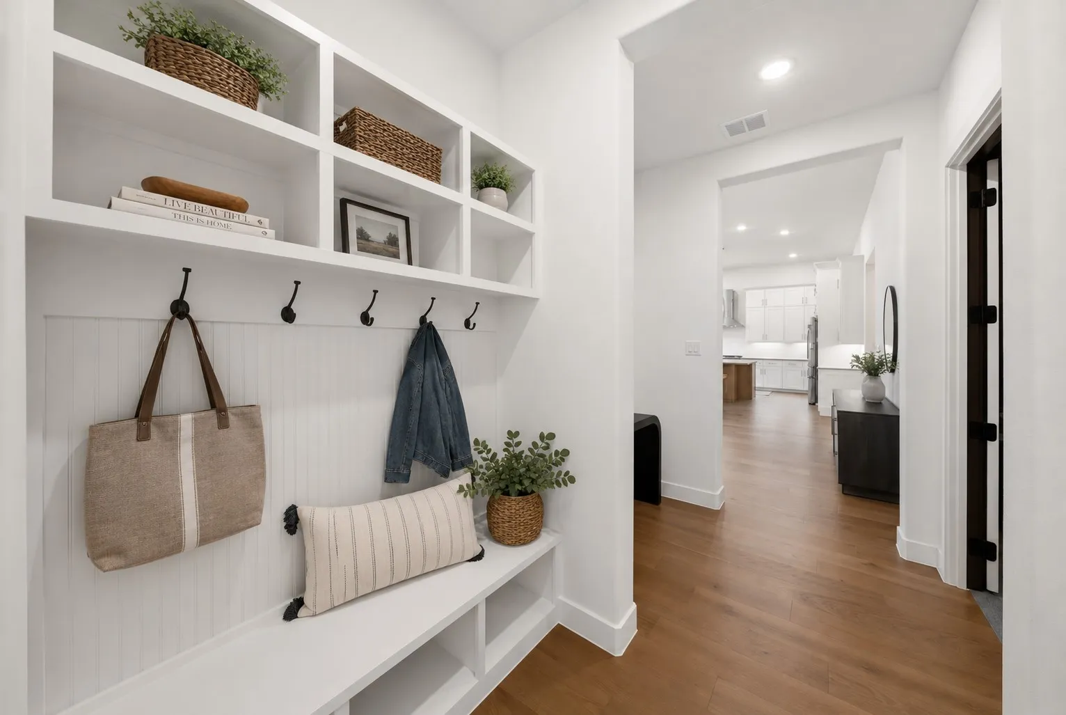 Elegant mudroom featuring custom built-in cabinetry with open shelving, shiplap wainscoting, and integrated hooks for coats and bags