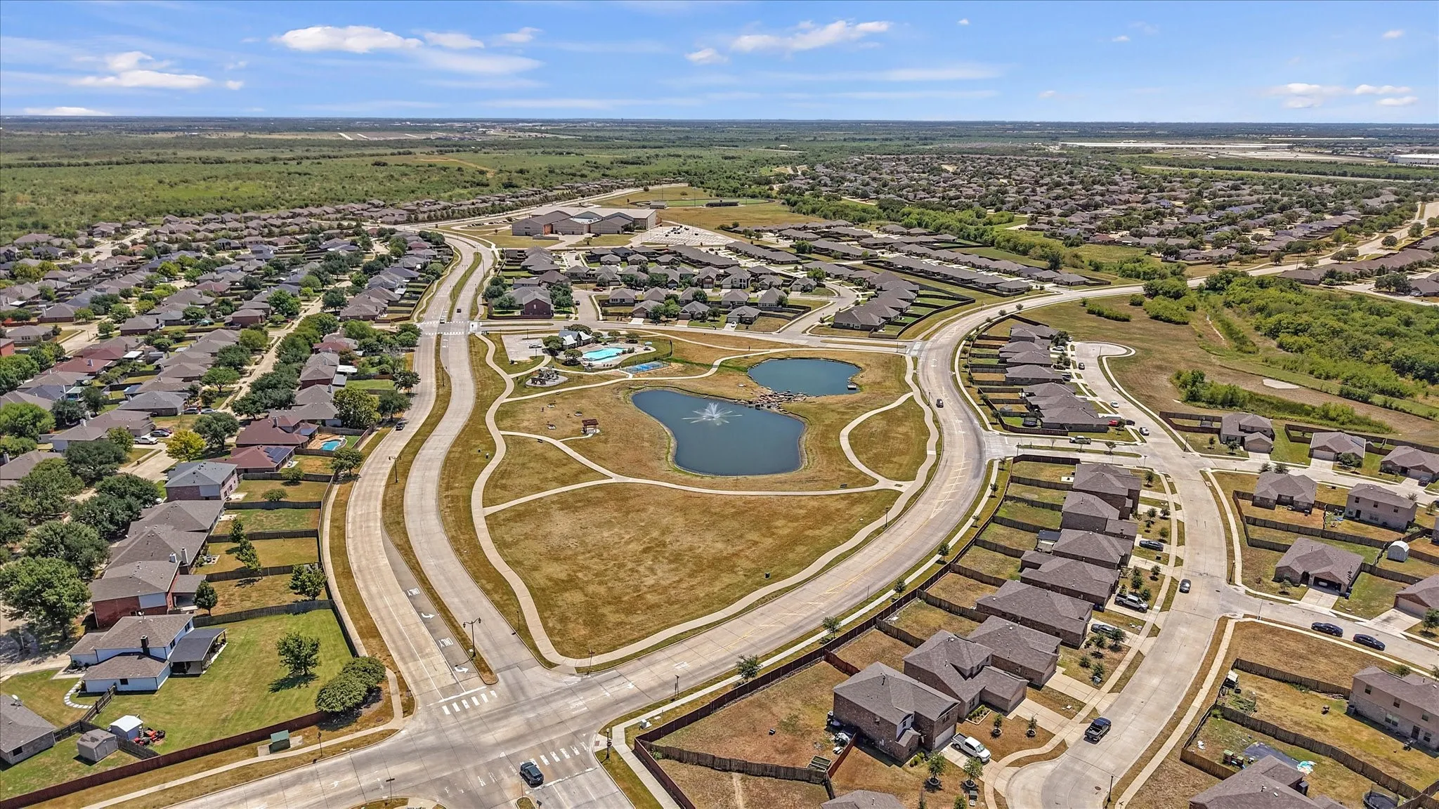 Neighborhood featuring a central pond with fountain, paved walking paths, residential streets, and surrounding homes