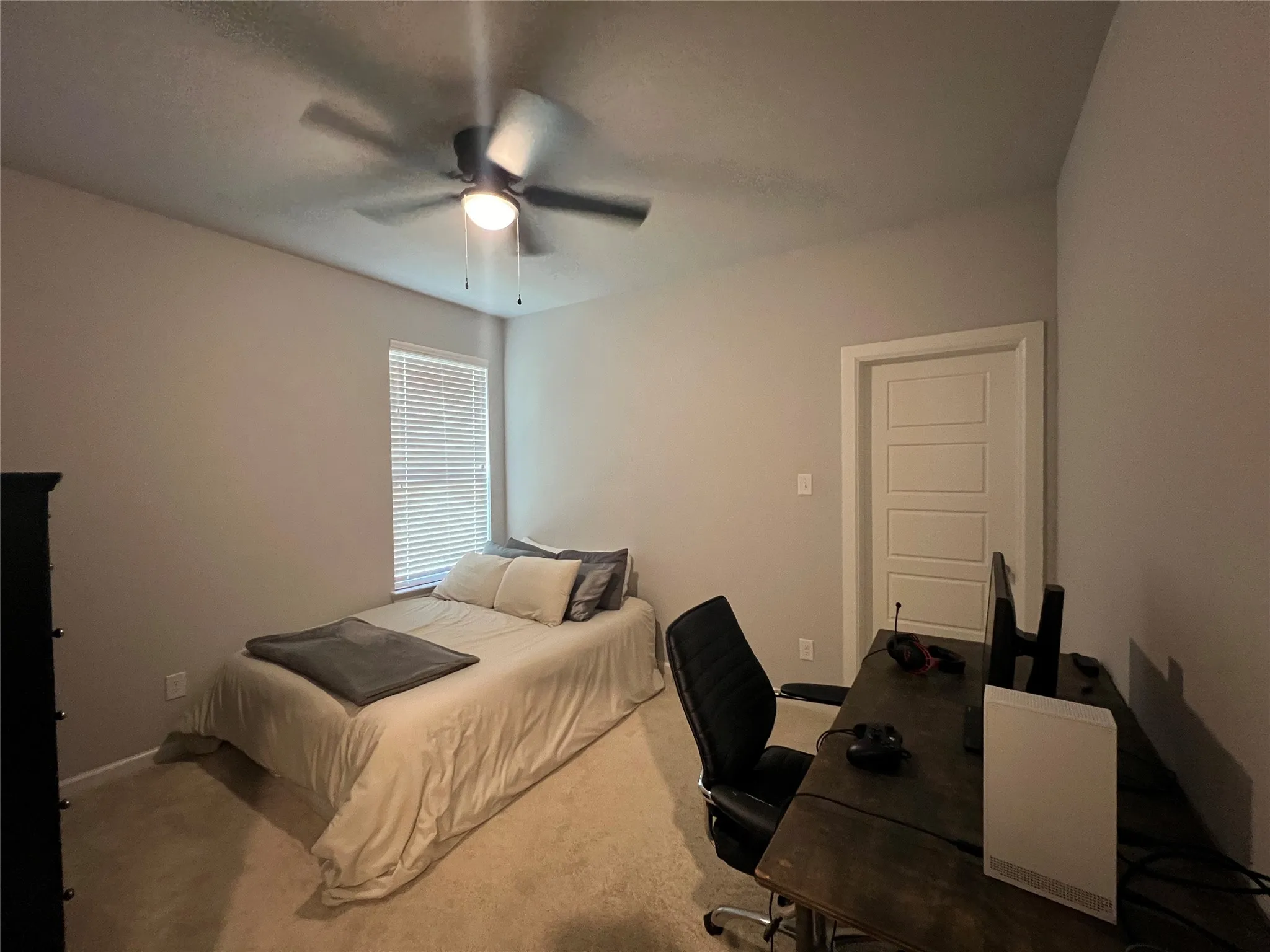 Carpeted bedroom featuring an office area and a ceiling fan