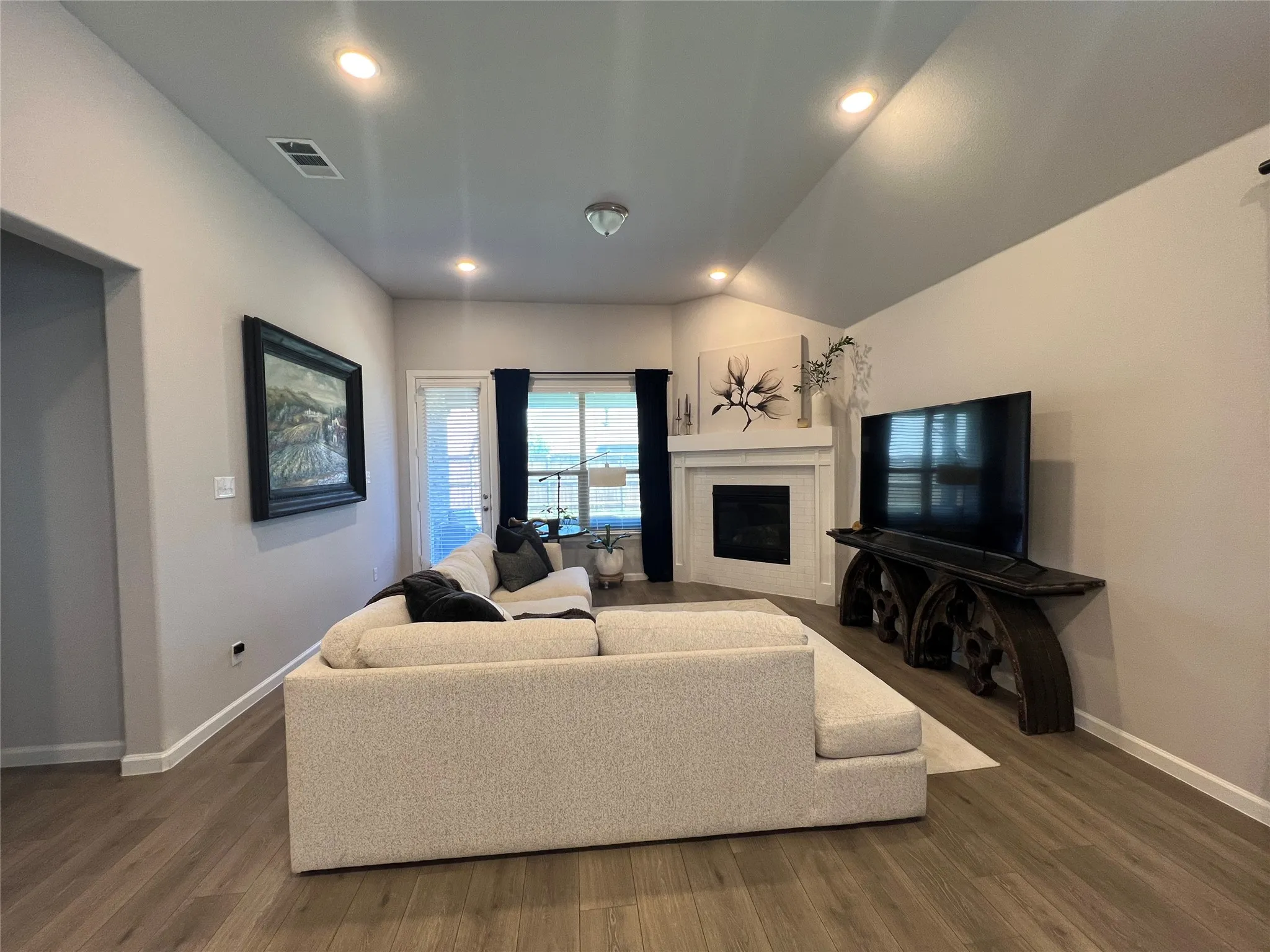 Living area featuring dark wood-style floors, a fireplace, recessed lighting, and lofted ceiling