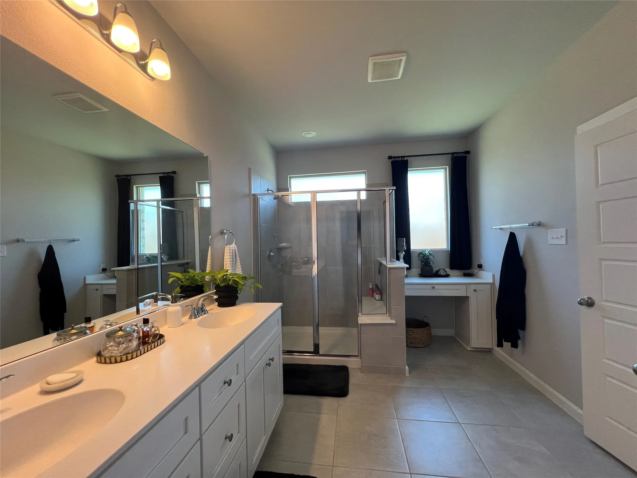 Full bath with double vanity, a stall shower, and tile patterned flooring
