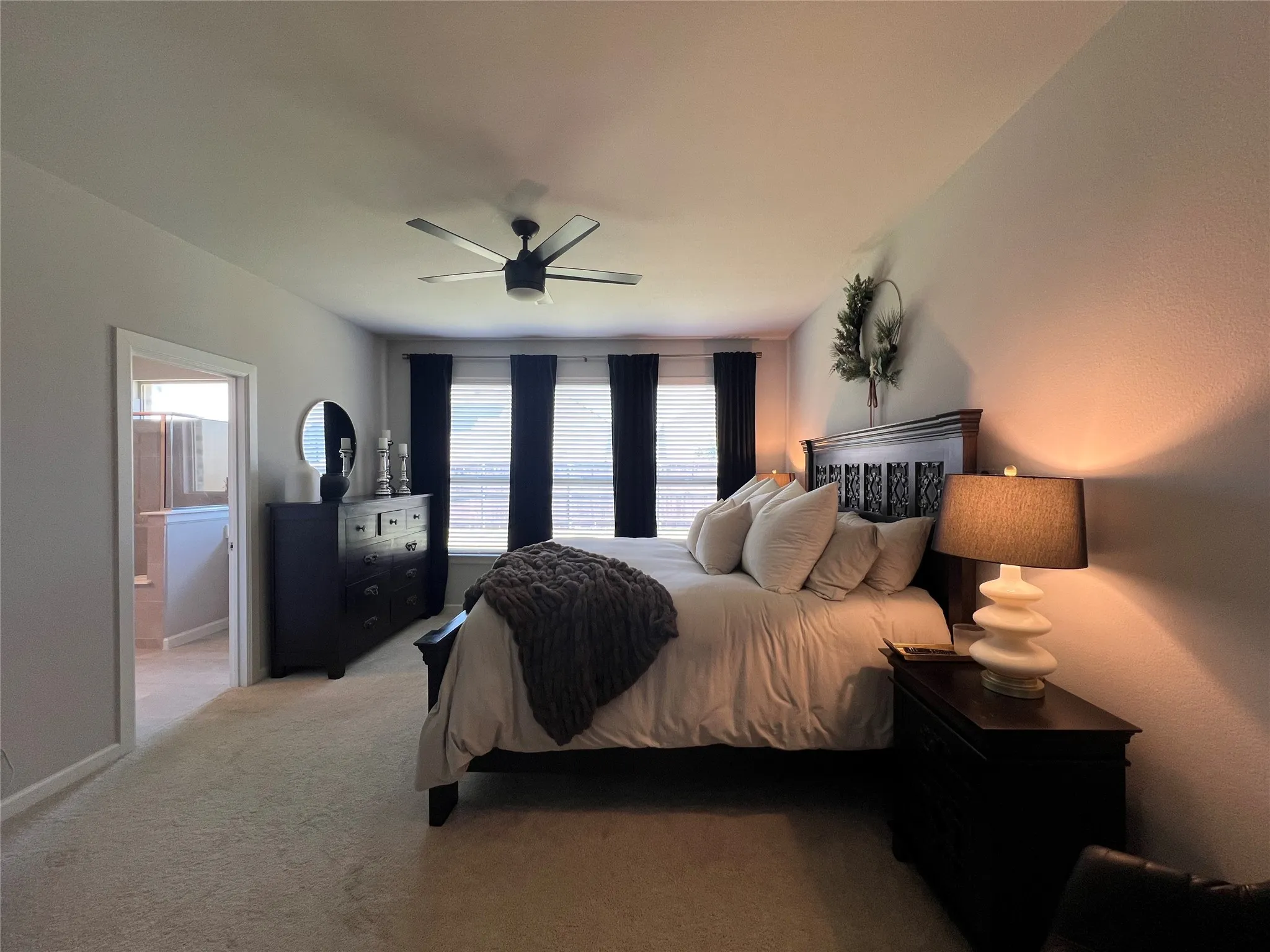 Bedroom with light carpet, ceiling fan, and connected bathroom