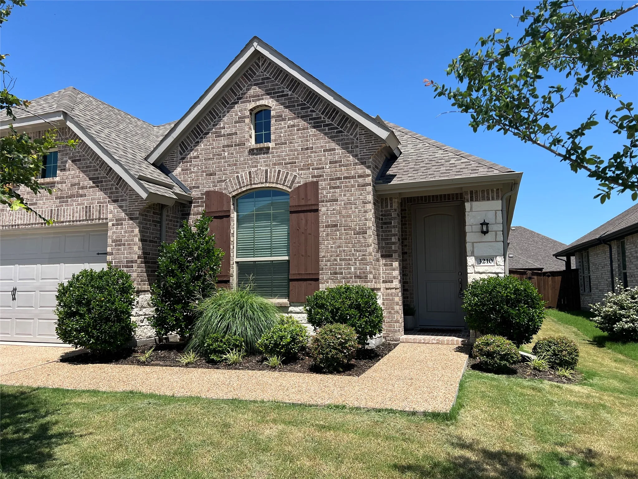 French country inspired facade featuring brick siding and a shingled roof