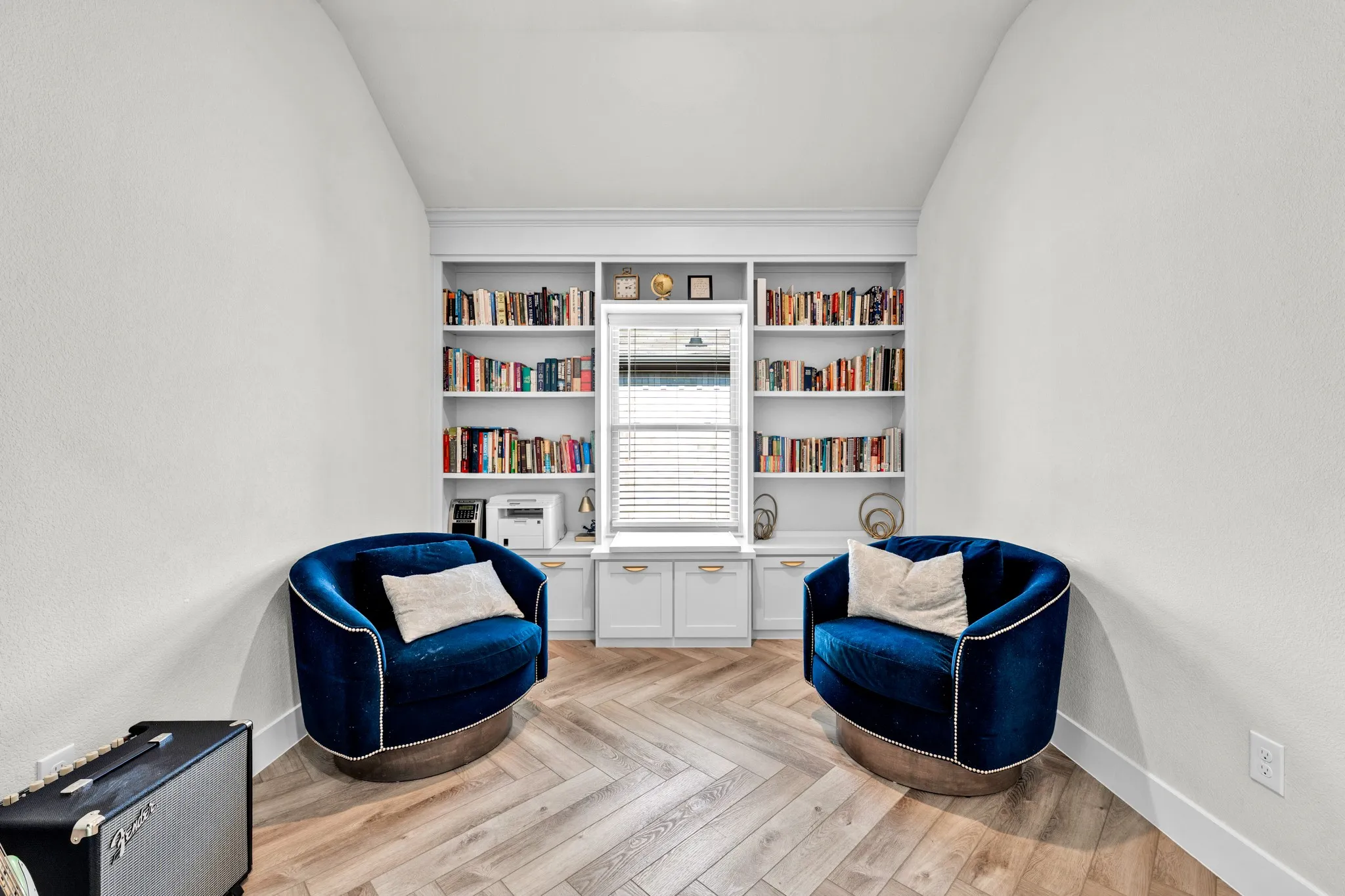 Built-in shelving with lower cabinetry, wood-finish flooring in a herringbone pattern, window with horizontal blinds, and recessed ceiling lighting
