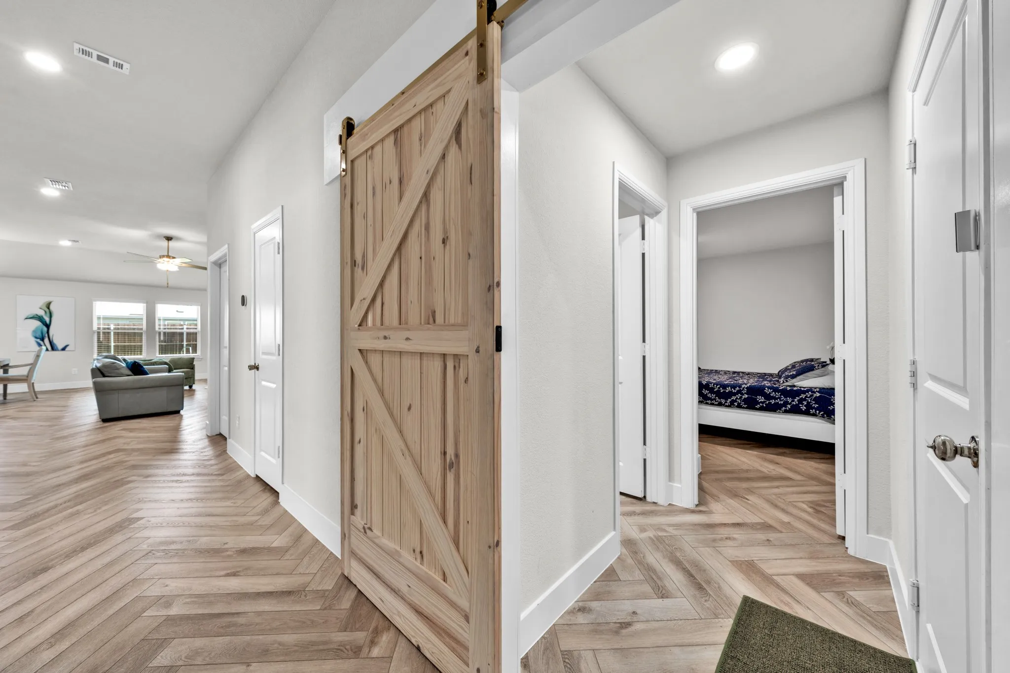 Herringbone wood-finish flooring throughout, modern wood barn door, recessed lighting