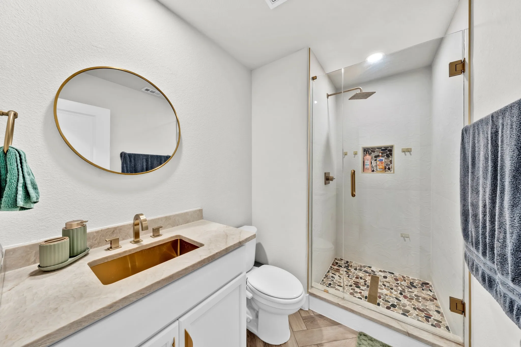 Walk-in shower with clear glass enclosure and pebble-tiled floor