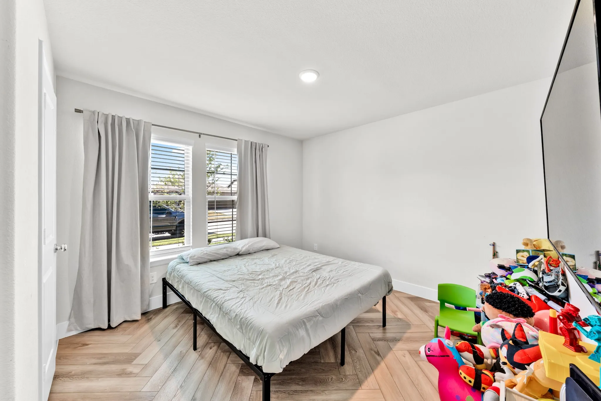 Wood-finish flooring in a herringbone pattern, double windows with blinds