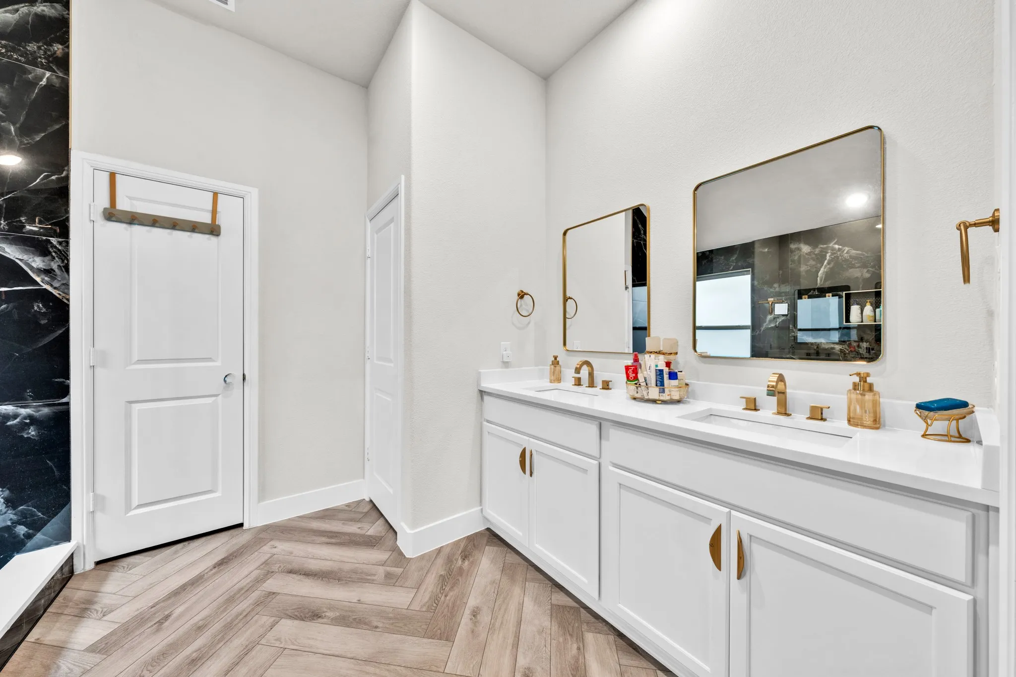 Dual vanity with white cabinetry, gold-finish hardware, and a solid surface countertop