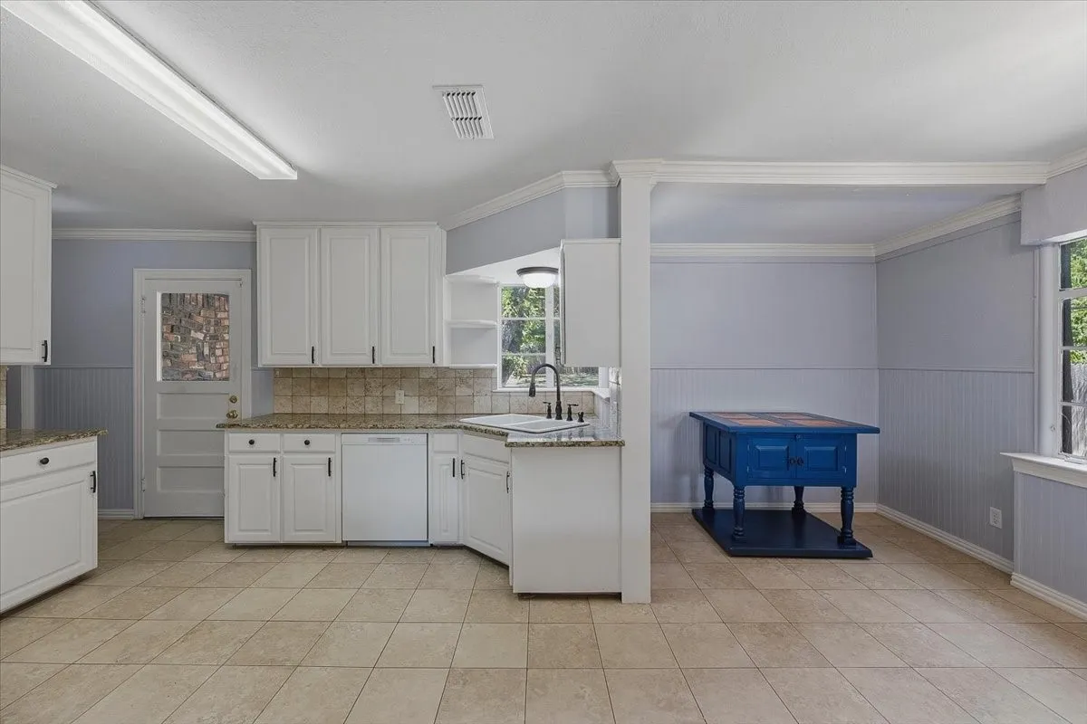 Charming brick ranch home set on manicured grounds featuring a curved brick driveway, mature landscaping with sculpted hedges, and established shade trees