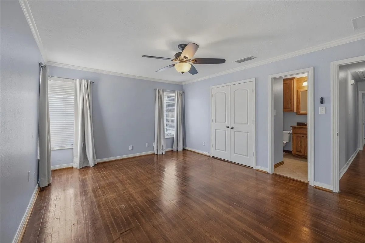 Hardwood flooring throughout, recessed lighting, crown molding, double-door closet, and ceiling fan with integrated lighting