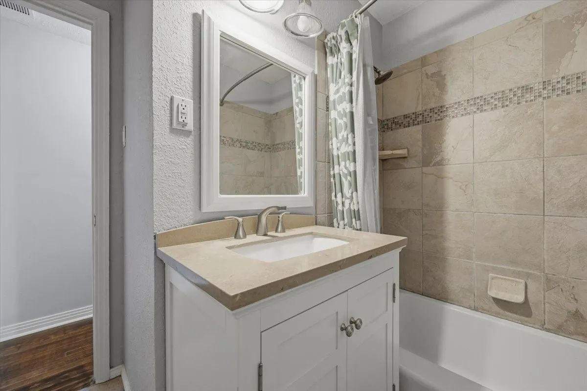 White vanity with brushed nickel hardware, light-toned countertop, and integrated sink