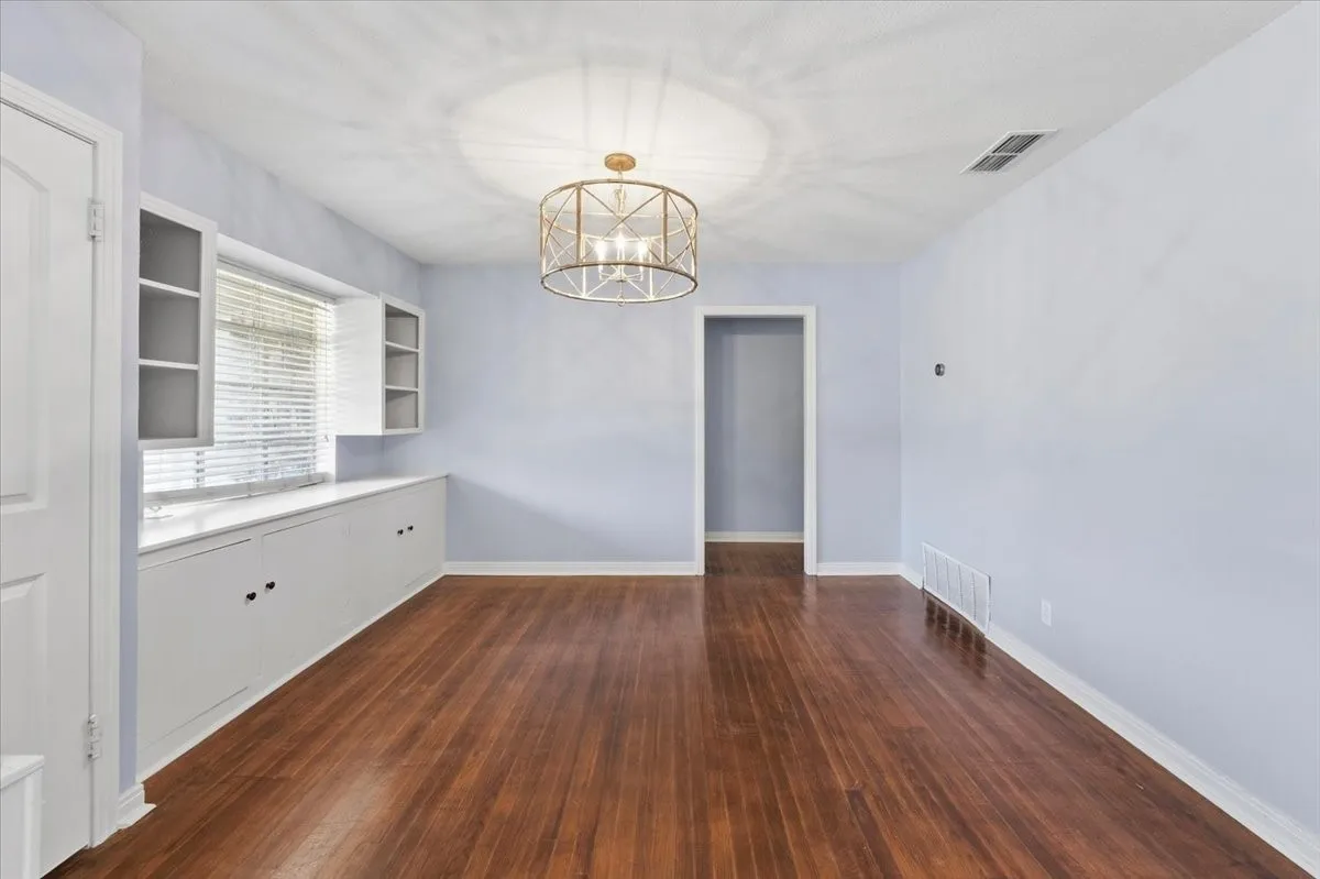 Wood-finish flooring, built-in cabinetry with glass-front uppers, and a decorative ceiling fixture