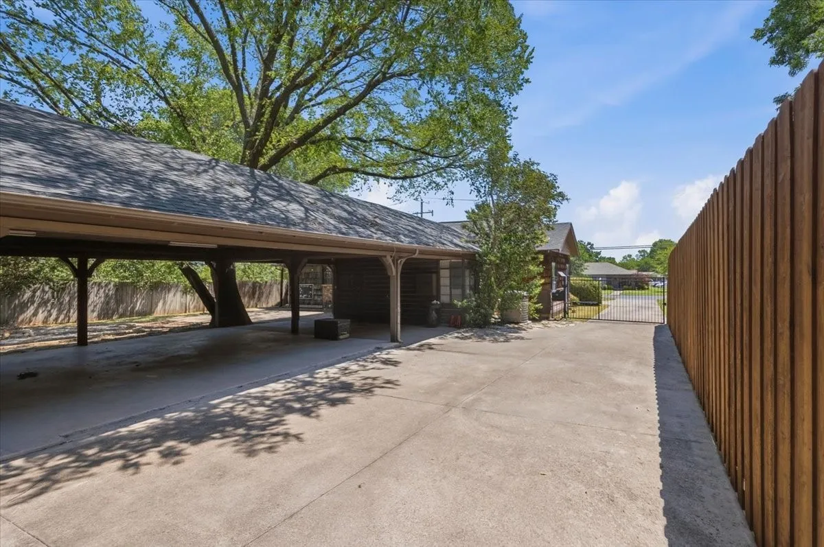 Expansive yard with mature trees, perimeter wood fencing, and a detached structure