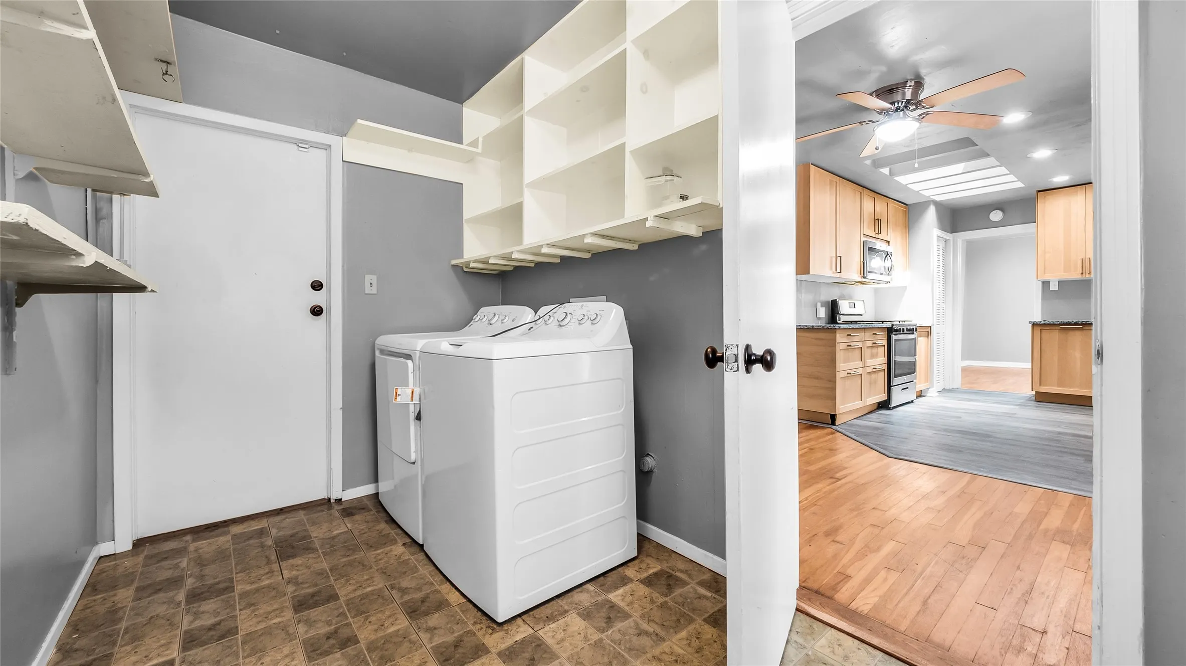 Laundry area featuring built-in shelving, durable flooring, and a solid exterior door