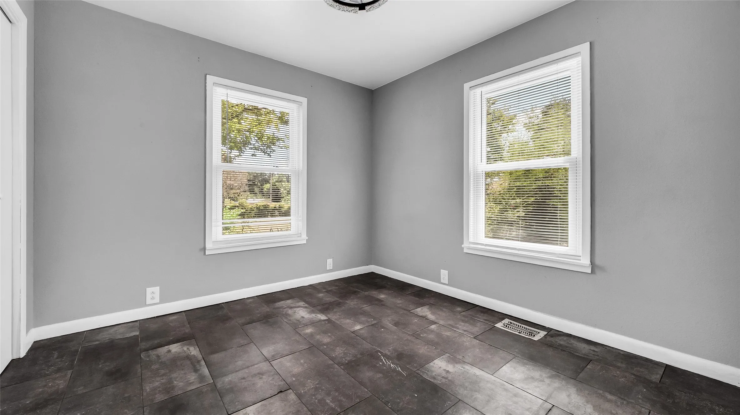 Two windows with blinds, dark wood-finish flooring, and recessed lighting