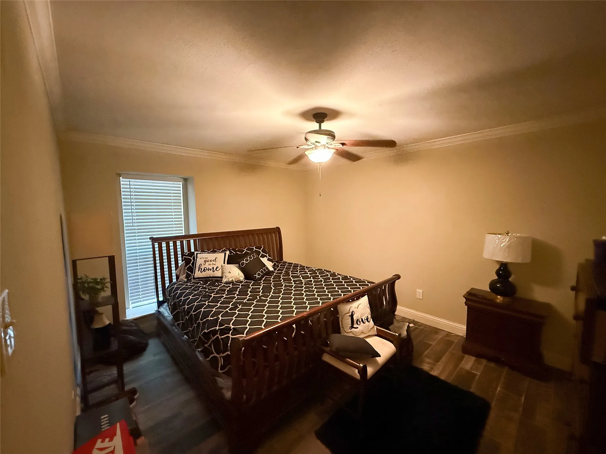 Wood-finish flooring, crown molding, ceiling fan with integrated lighting, and a single window with blinds