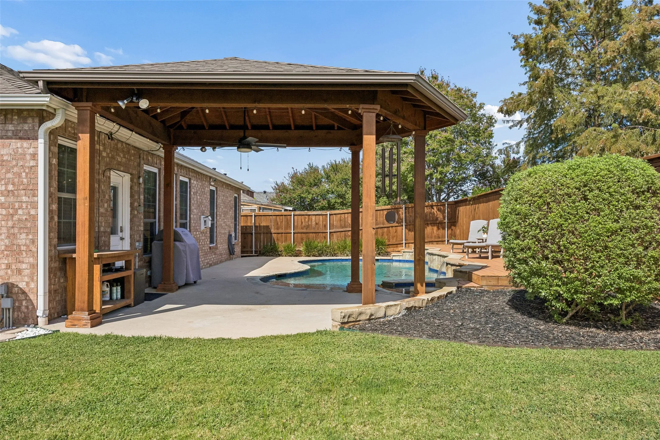 Covered Outdoor Space Plus Green Lawn - Beyond the pool area, the covered patio overlooks a generous stretch of grass, giving this oversized backyard a useful combination of shaded living space, recreation, and open lawn.